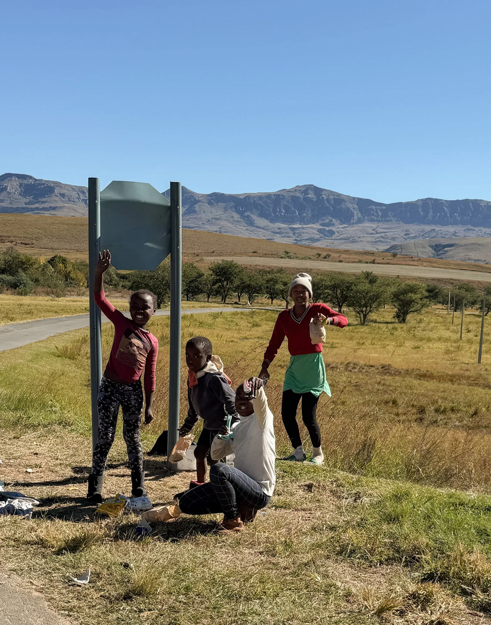 Kinderen langs een weg met uitzicht op de Drakensbergen in Zuid-Afrika