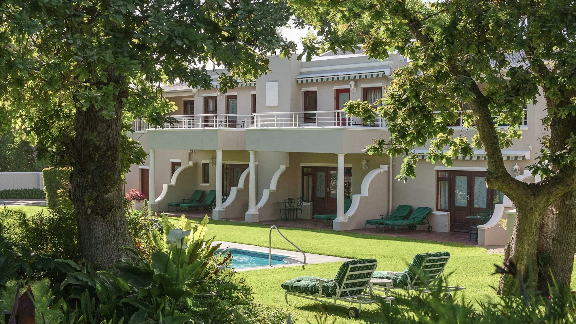 Glen Avon Hotel in Constantia met een groene tuin, ligbedden en een deel van het zwembad.