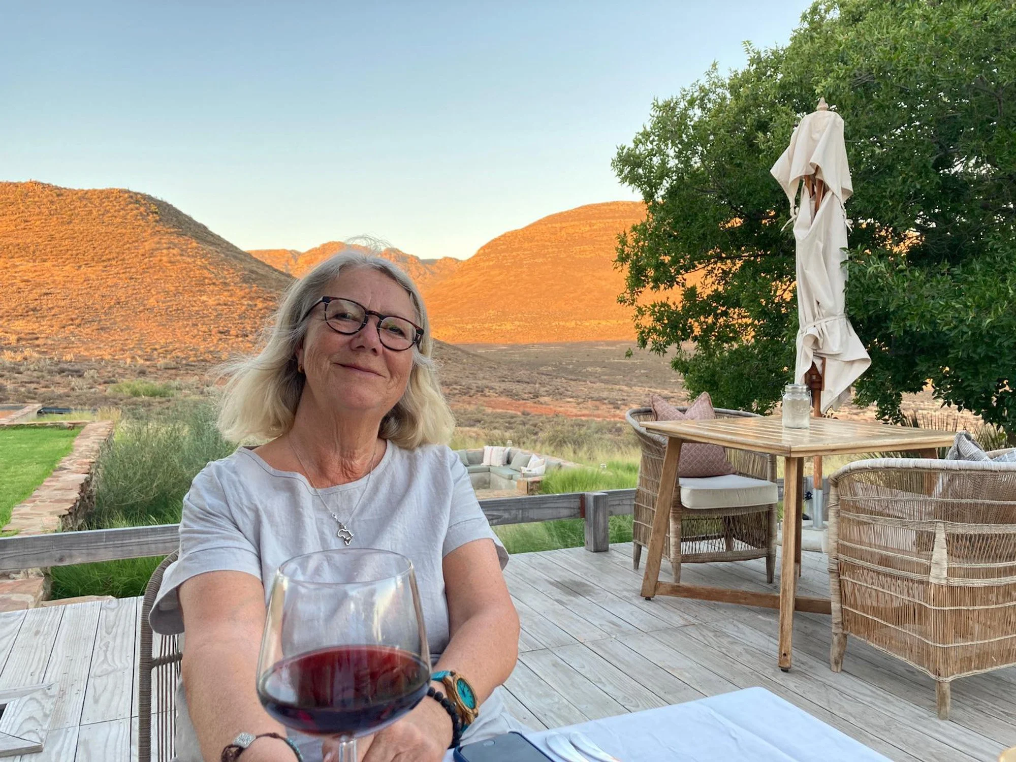 Marjolein Westerterp van Oog voor Afrika met glas rode wijn op terras in Zuid-Afrika.