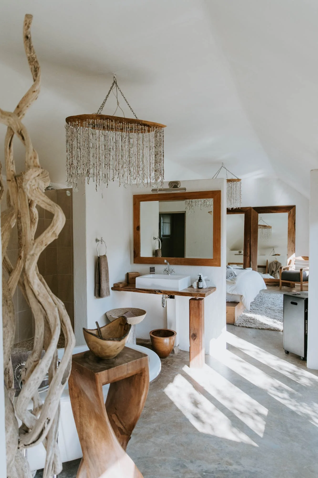 Open badkamer van Qambathi Mountain Lodge met houten wastafel, vrijstaand bad en kralenlampen.