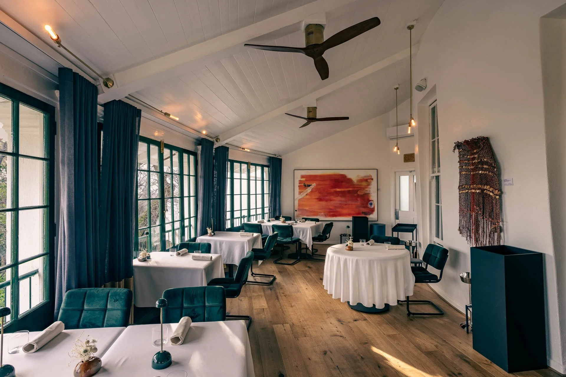Restaurantinterieur met ronde tafels, witte tafellakens en hoge ramen in Zuid-Afrika.