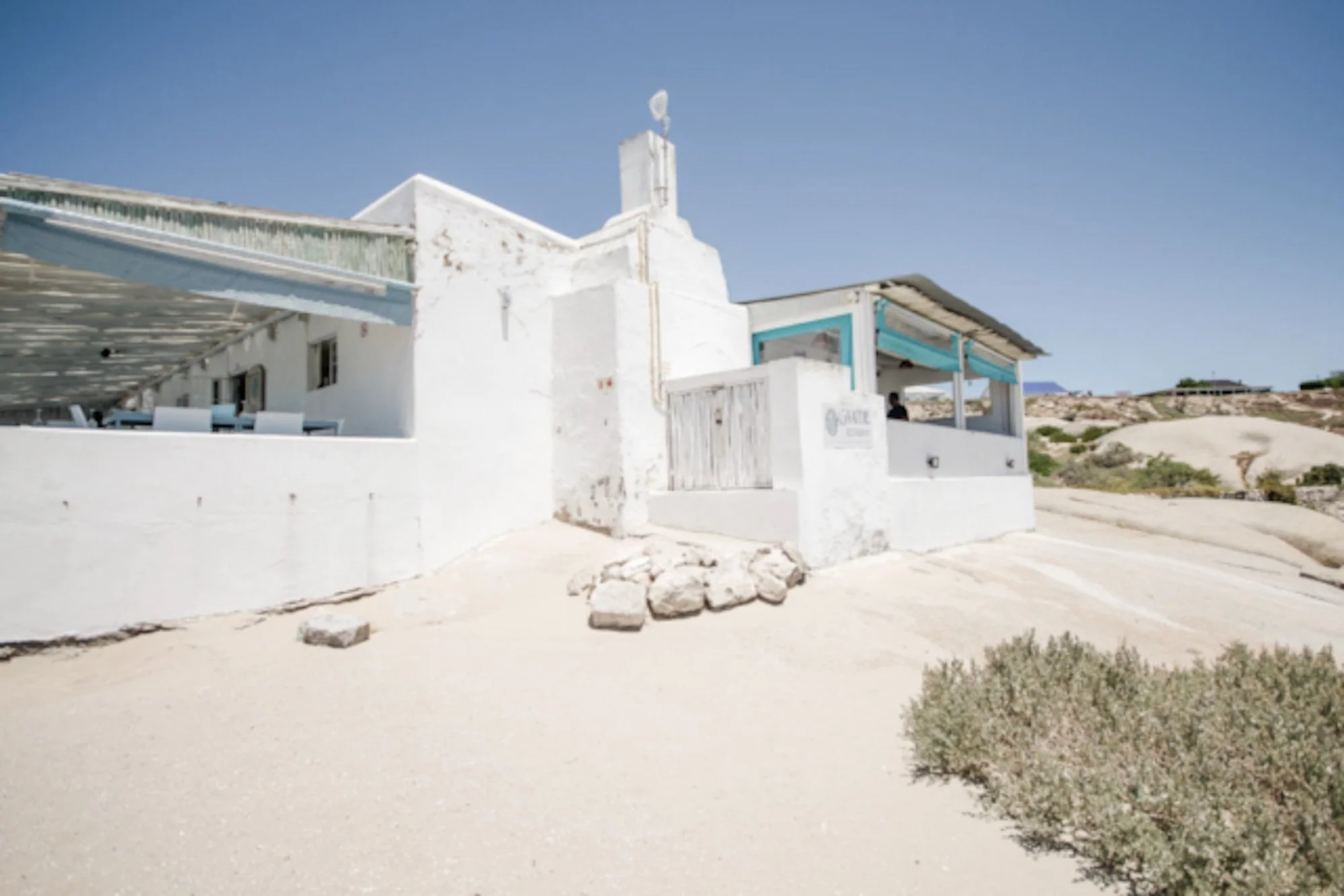 Wit restaurantgebouw van Gaaitjie in duinlandschap aan de kust.