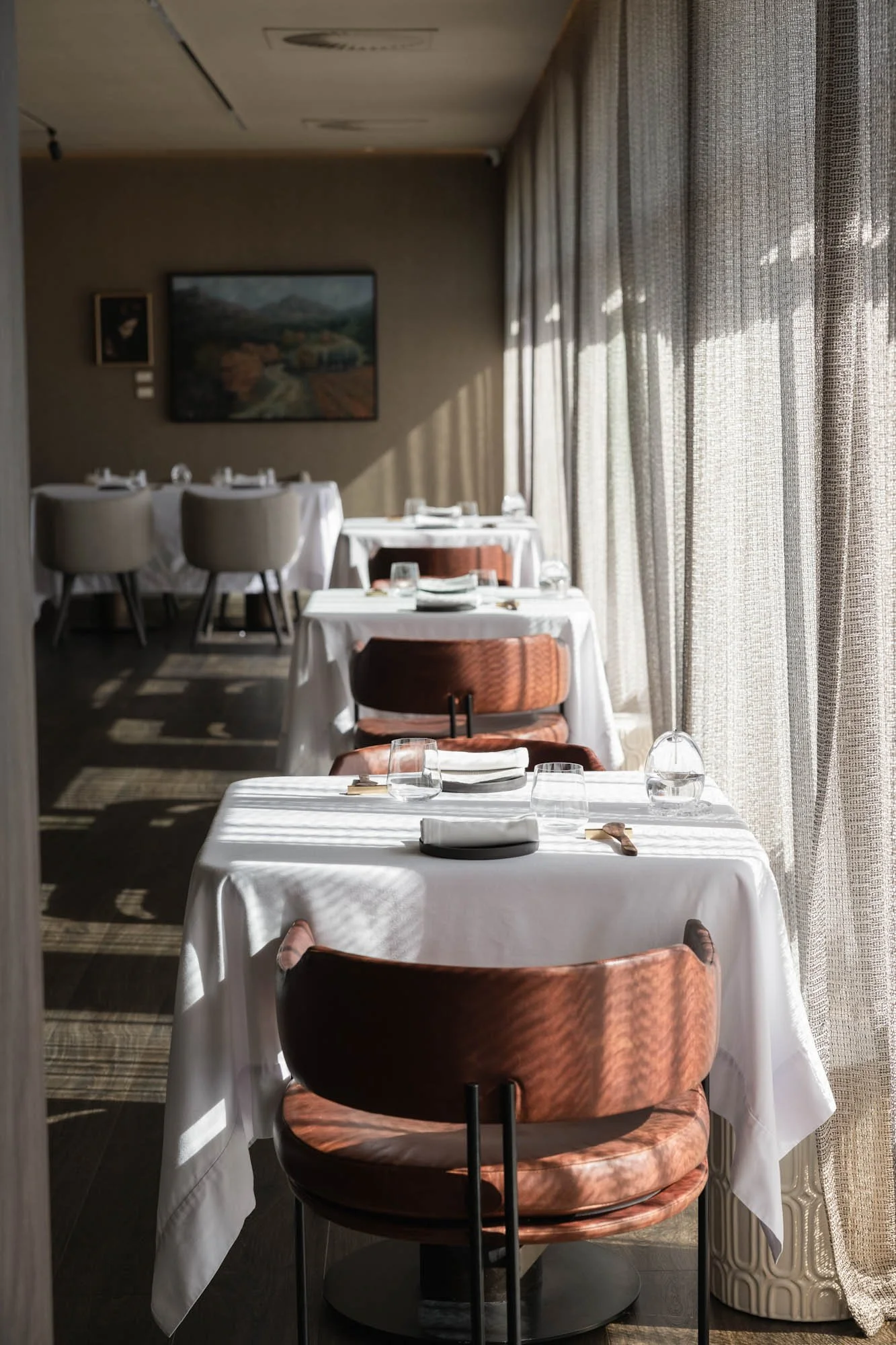 Licht restaurantinterieur van Mertia in Stellenbosch met ruim opgestelde tafels en zonlicht door de gordijnen.
