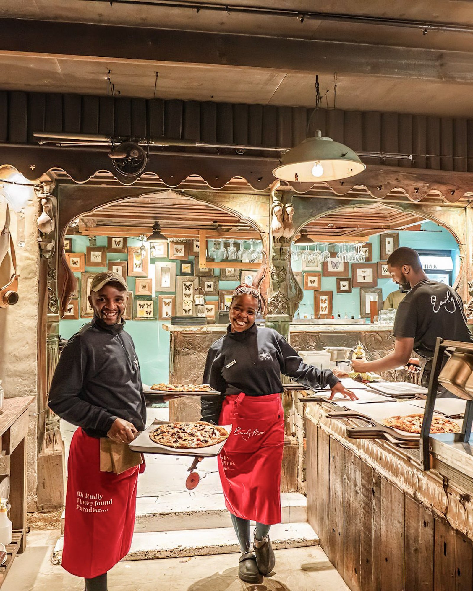 Restaurantmedewerkers lopen met pizza’s door restaurant in Plett.