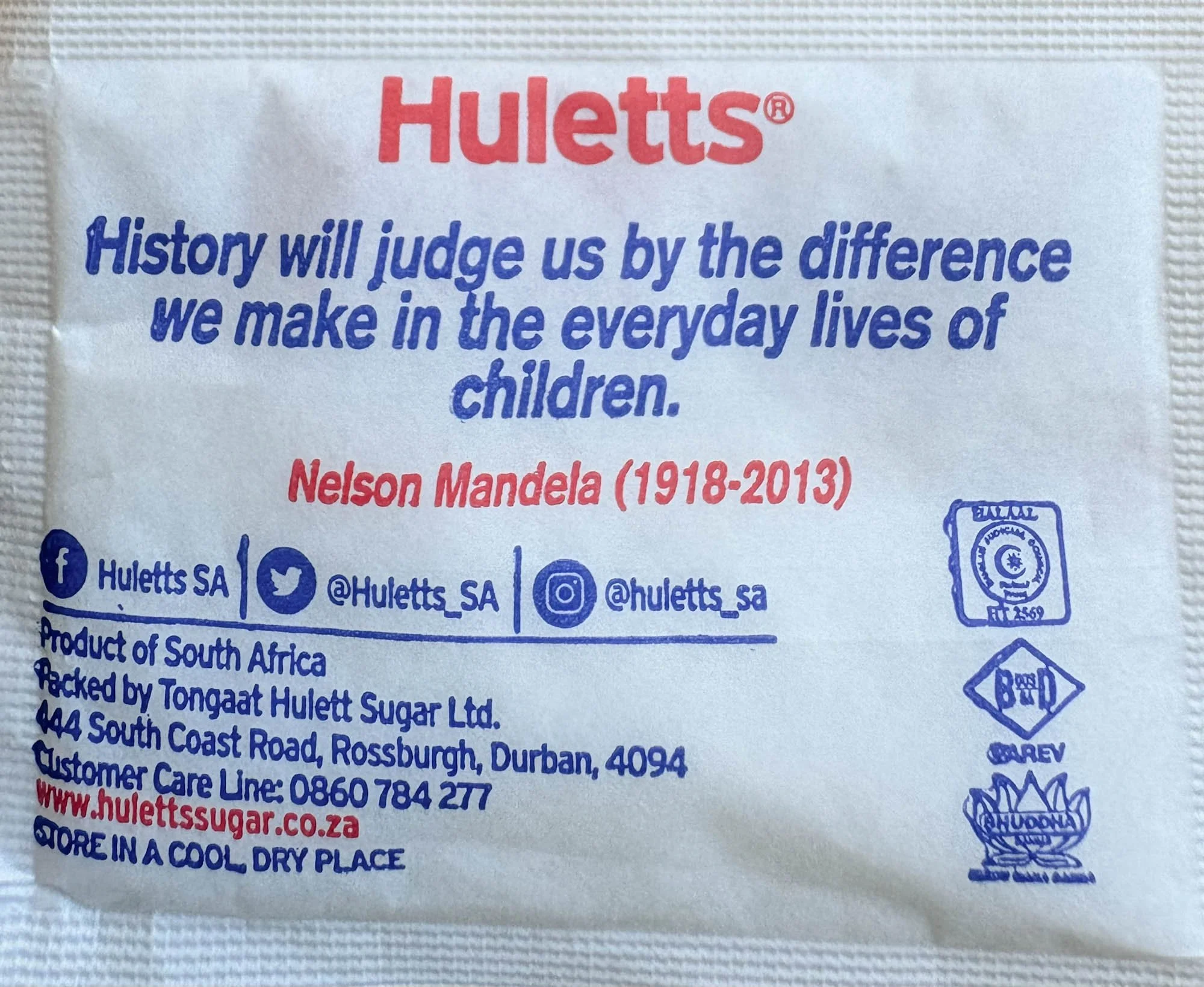 Achterkant van suikerzakje toont een spreuk van Mandela over zorgen voor kinderen.