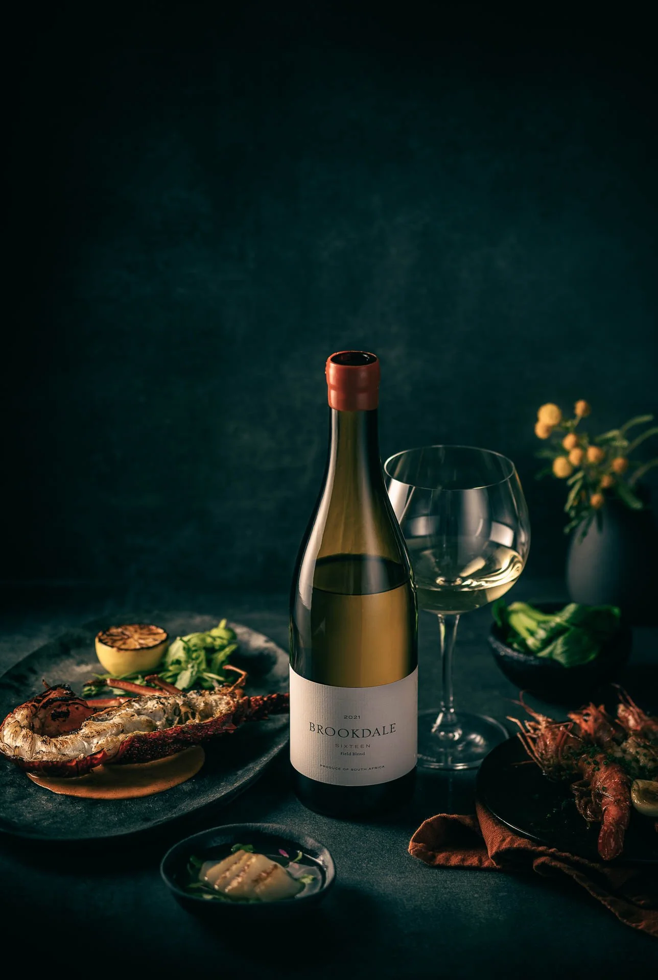 Fles witte wijn van Brookdale met glas op donkere achtergrond.