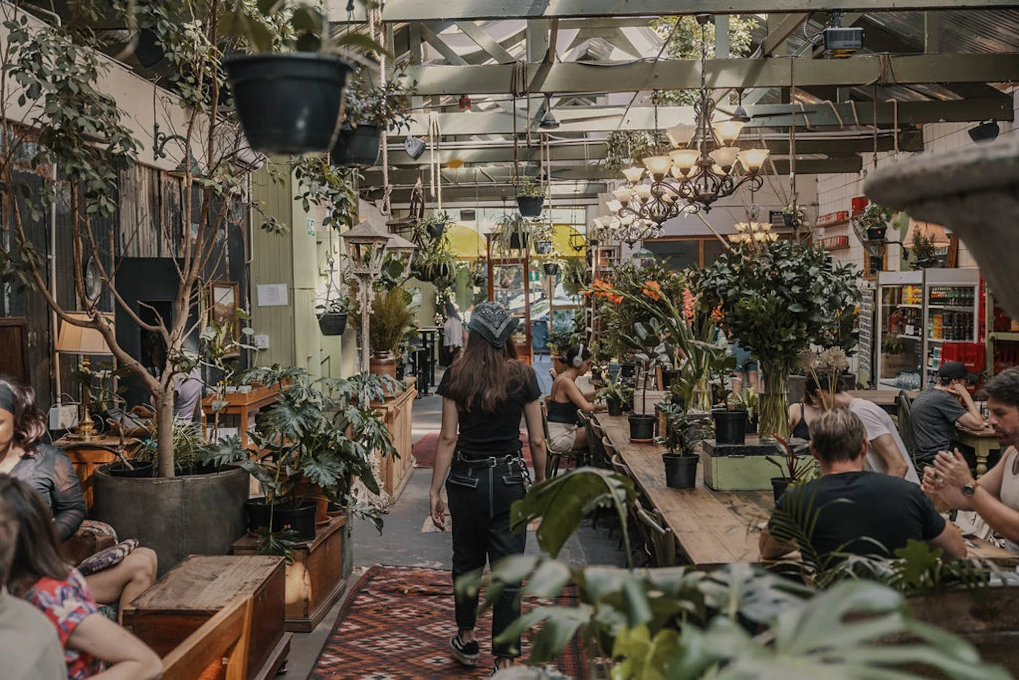 Gasten zitten tussen de planten en vintage meubels in het restaurant van Our Local in Kaapstad.