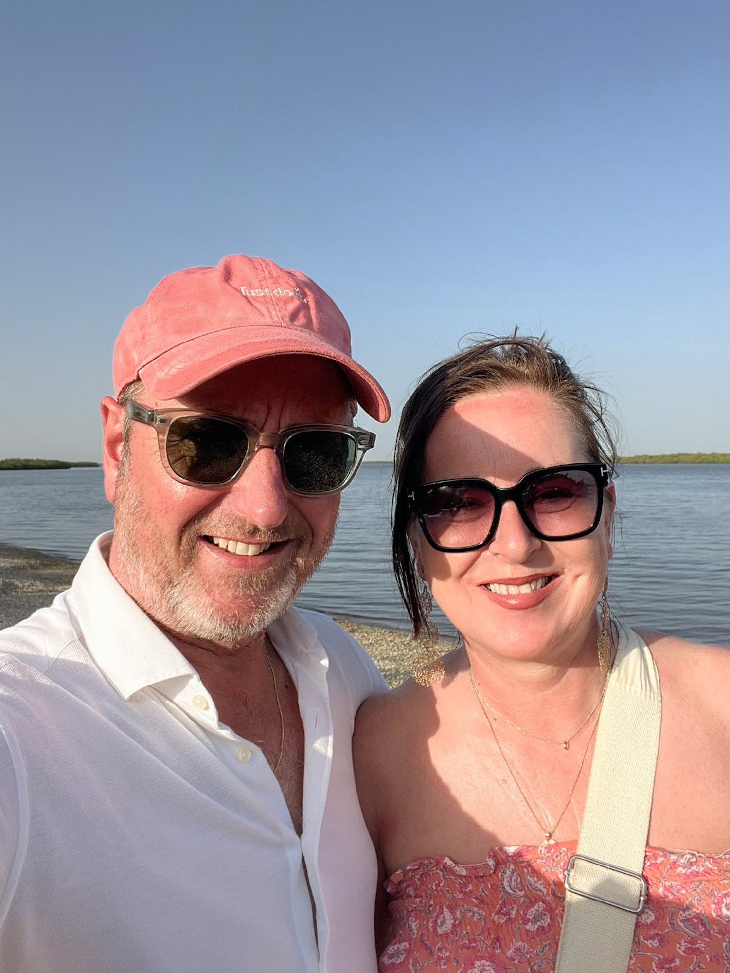 Twee mensen maken selfie bij water met kustlijn op de achtergrond in Afrika.