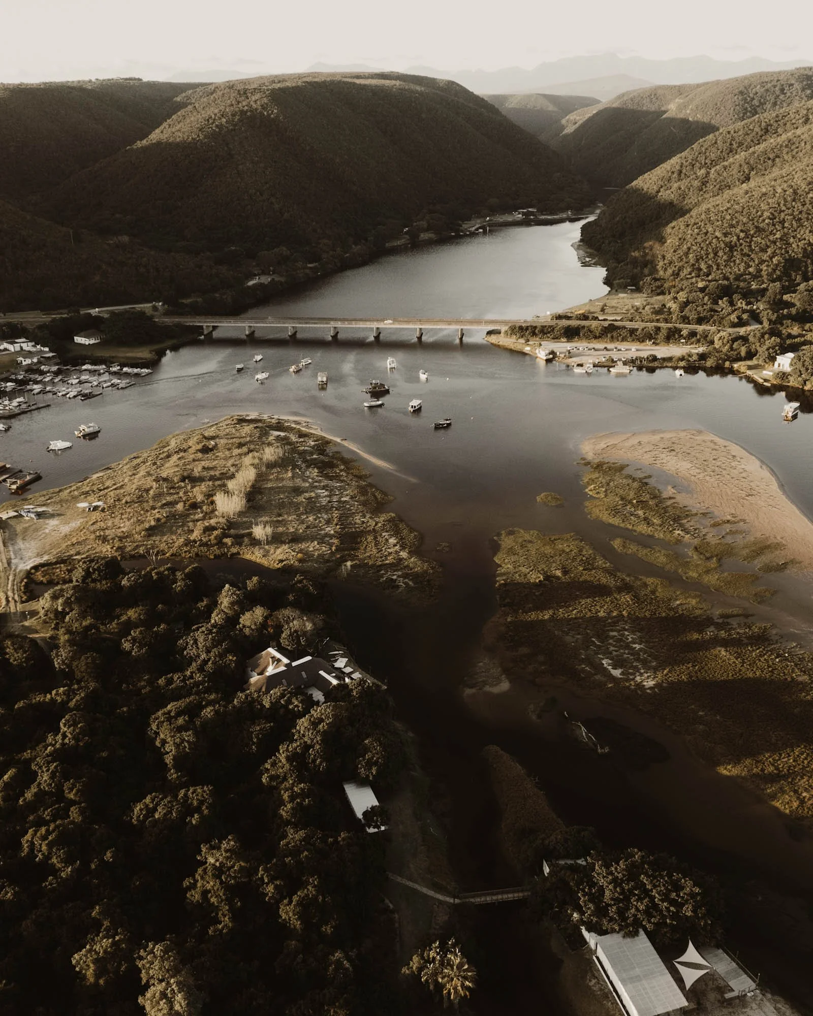 Luchtfoto van Stanley Island in de Keurbooms-rivier met de brug, boten en omliggende heuvels.