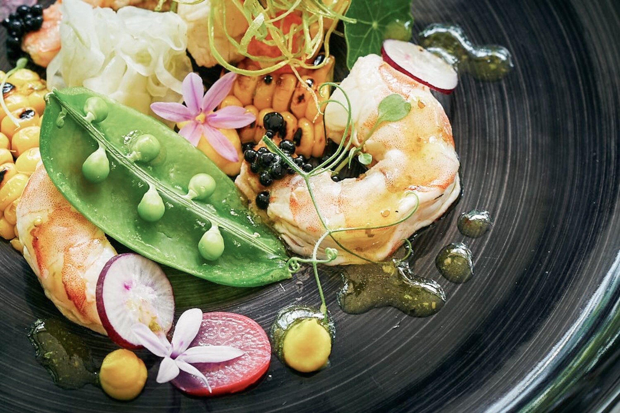 Creatief opgemaakt fine dining gerecht met garnalen, groenten en kruiden bij Prana Lodge in Zuid-Afrika.