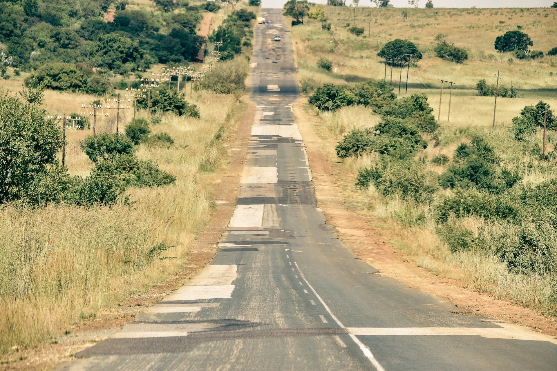 Lange rechte weg van slechte kwaliteit door open landschap in Zuid-Afrika.