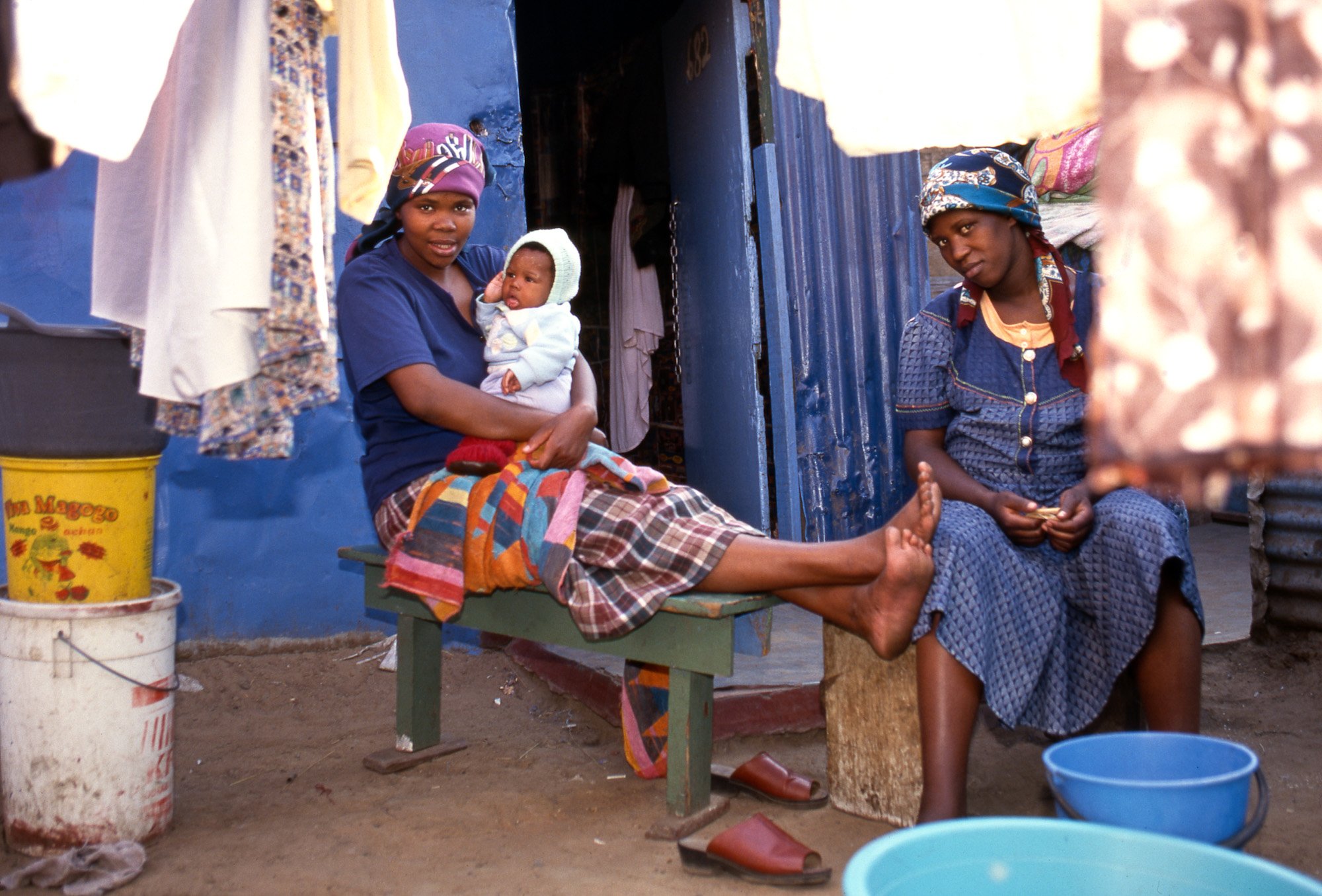 Soweto, Zuid-Afrika vrouwen voor huis van golfplaten met baby op schoot.