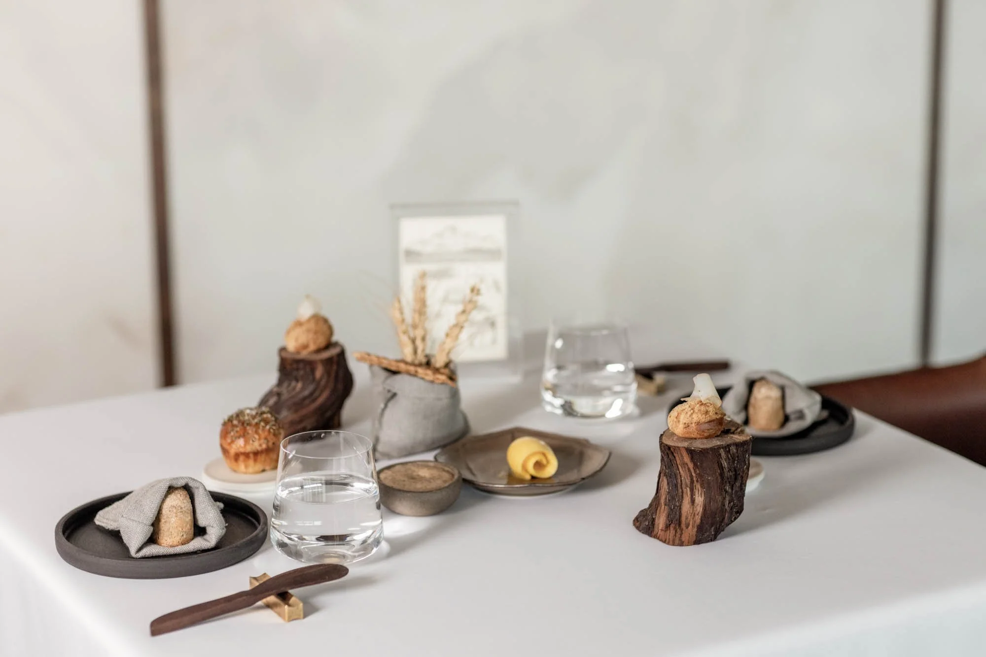 Gedekte tafel bij Mertia in Stellenbosch met brood, kleine hapjes en verfijnd servies.