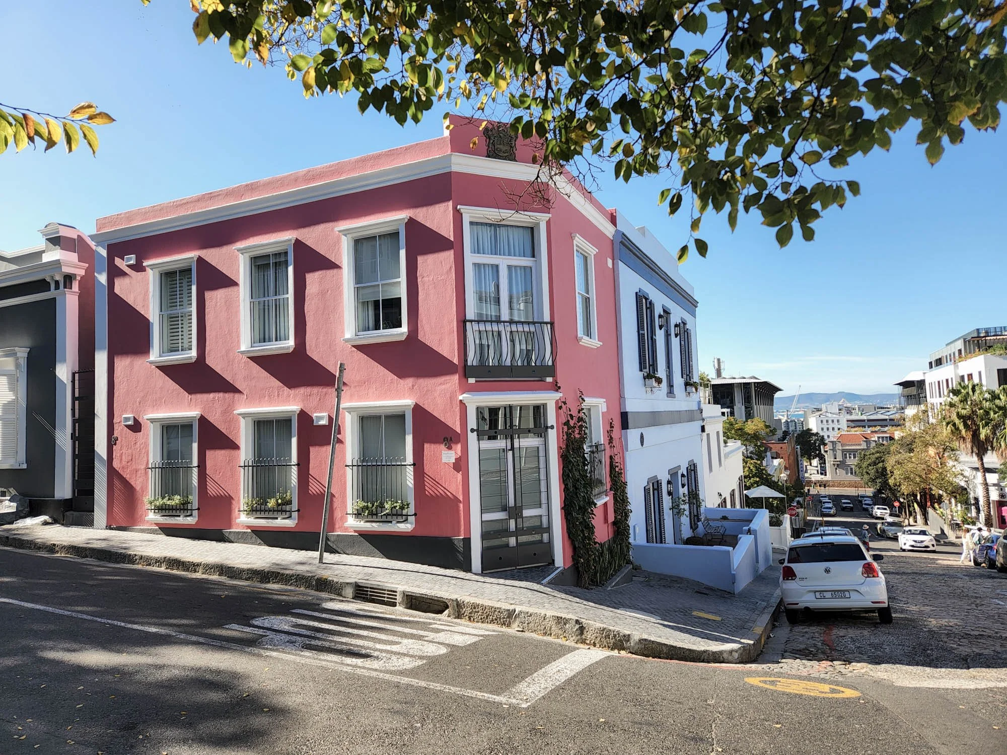 Roze gevel van een Loader 8 op een straathoek in de wijk De Waterkant in Kaapstad.