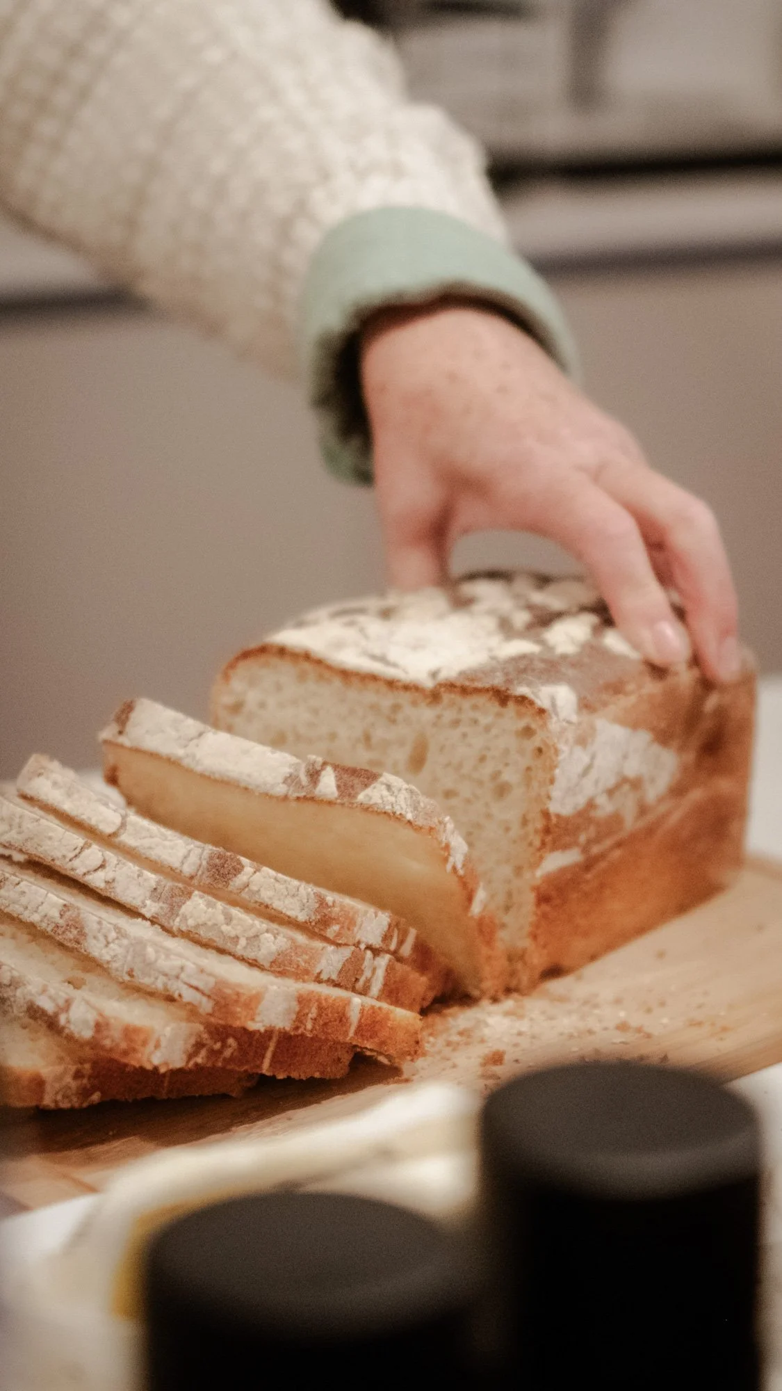 Hand snijdt vers brood op houten plank met kruimels in Zuid-Afrika.