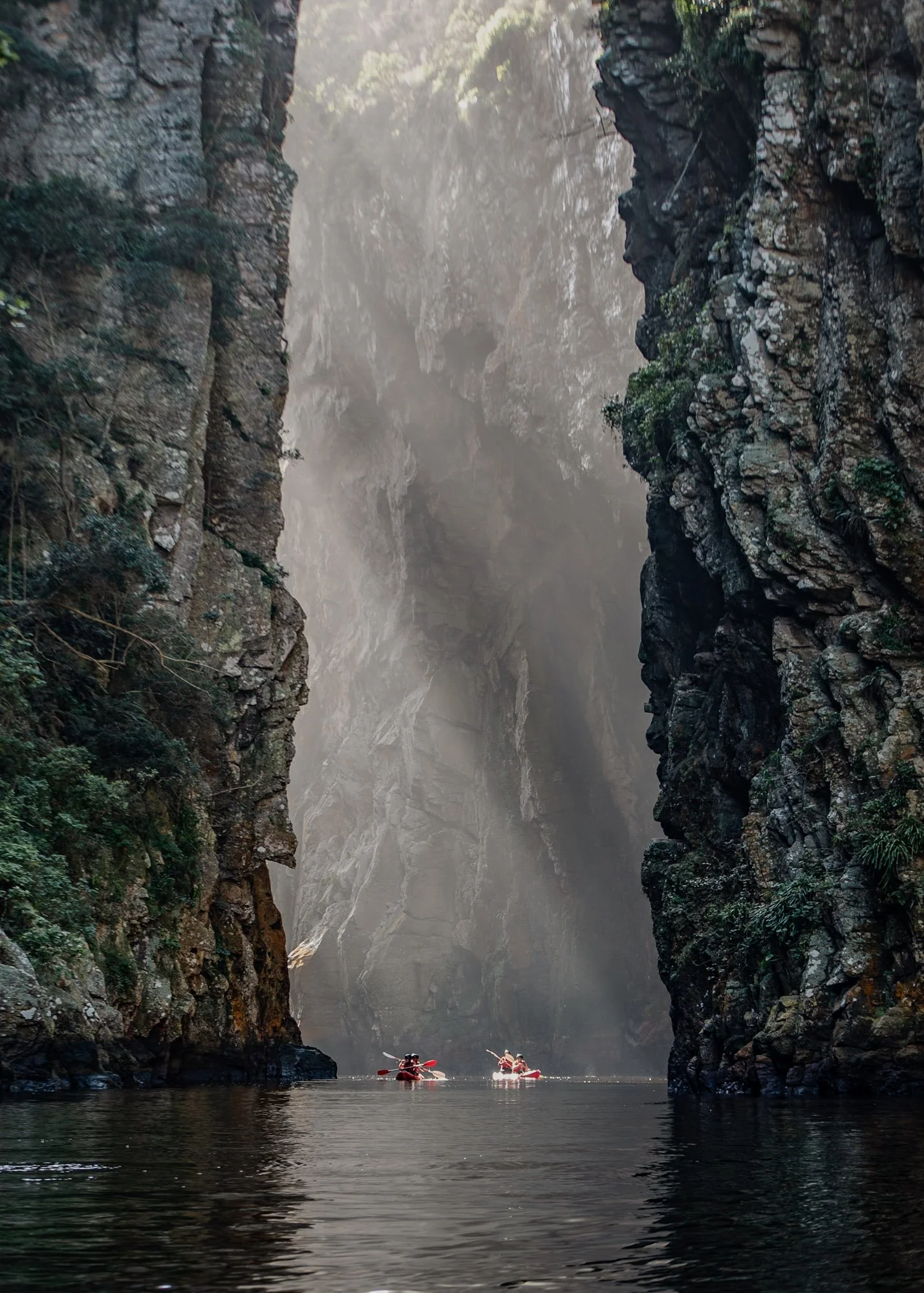 Kajakkers varen tussen hoge rotswanden door de Storms River Gorge in Tsitsikamma, Zuid-Afrika