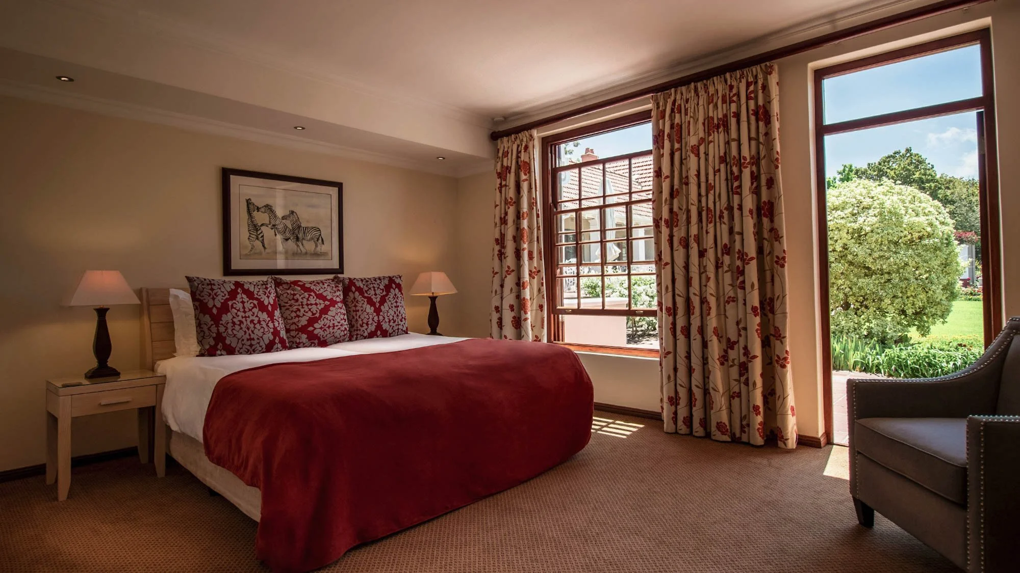 Sfeervolle kamer van Glen Avon Hotel met rood beddengoed en uitzicht op de tuin.