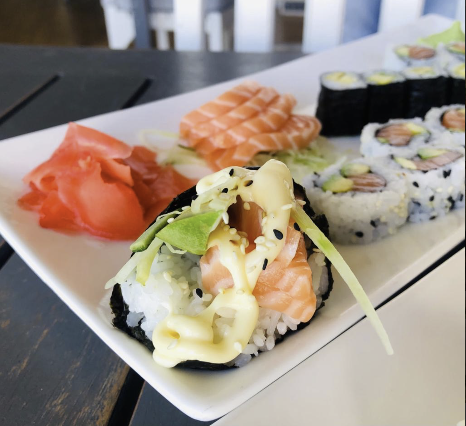 diverse soorten sushi en sashimi op een wit rechthoekig bord