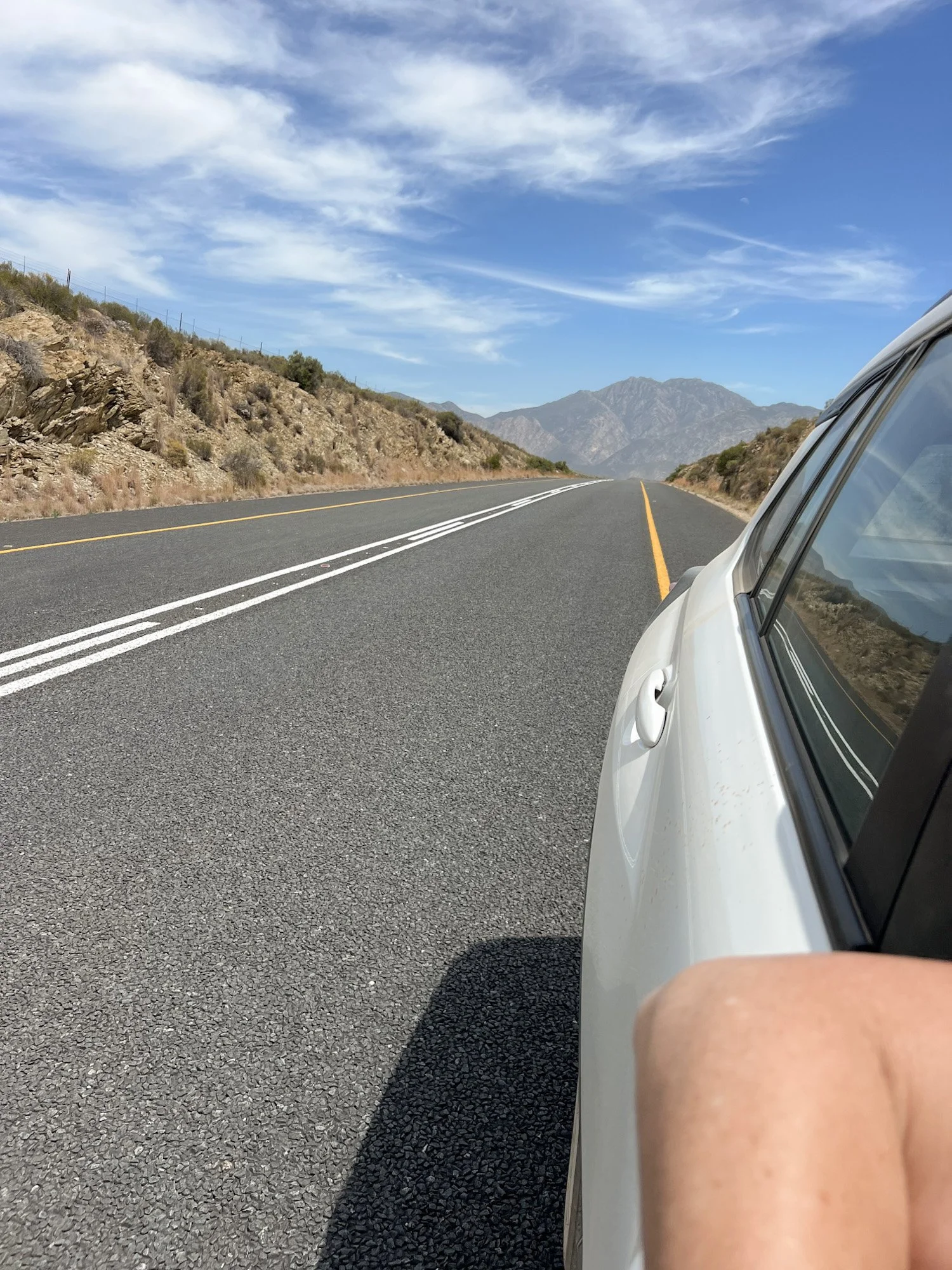 Autorit over een lege weg door bergachtig landschap in Zuid-Afrika.