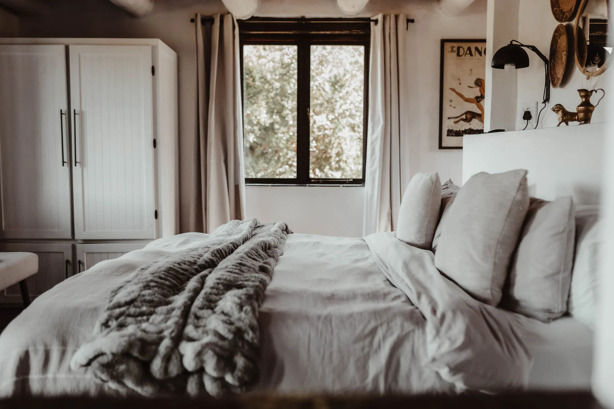 Lichte slaapkamer van Stanley Island met een opgemaakt bed, houten details en uitzicht op het groen.