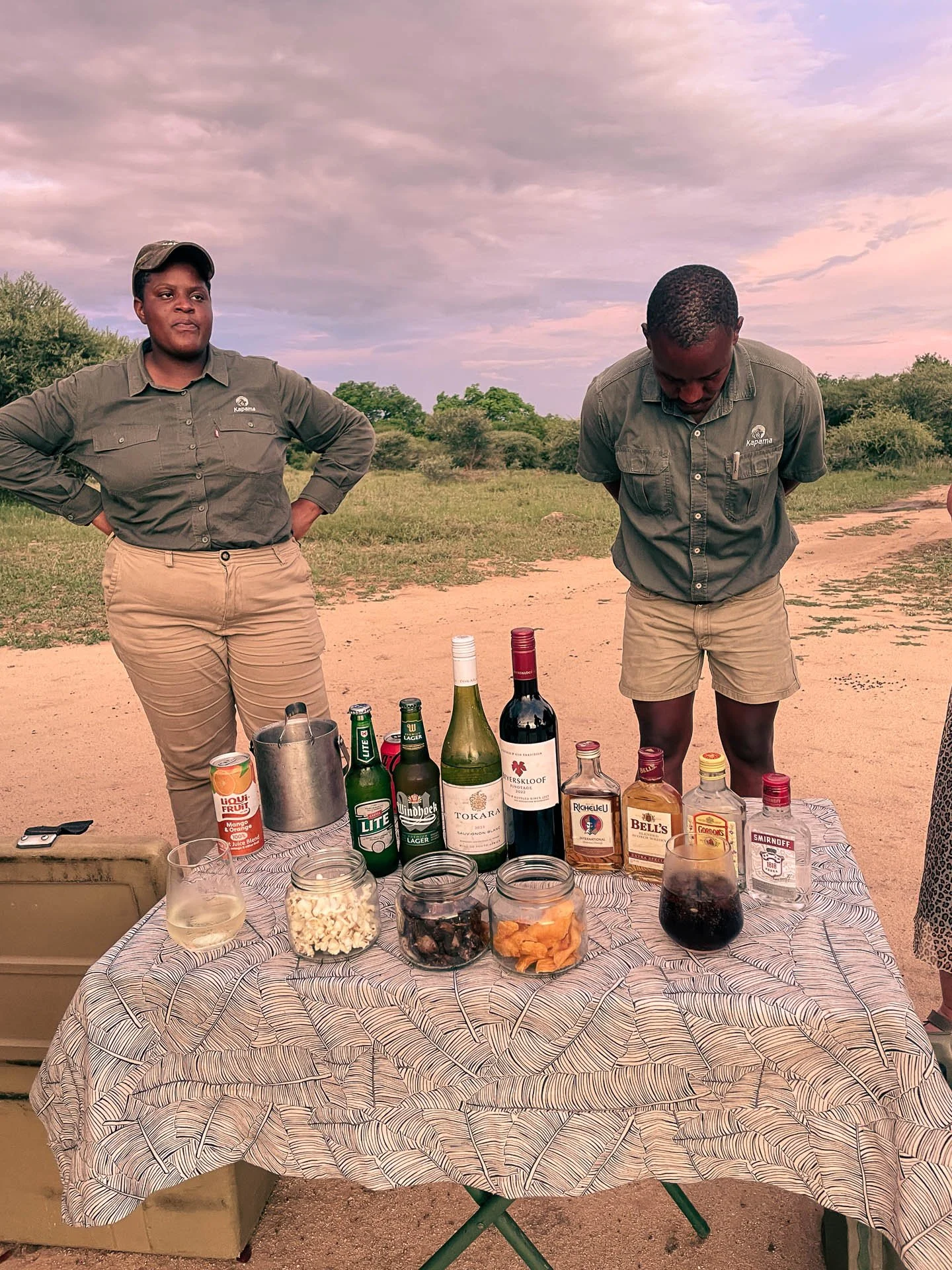 Rangers staan bij een sundowner-tafel met drankjes in de bush van Zuid-Afrika.