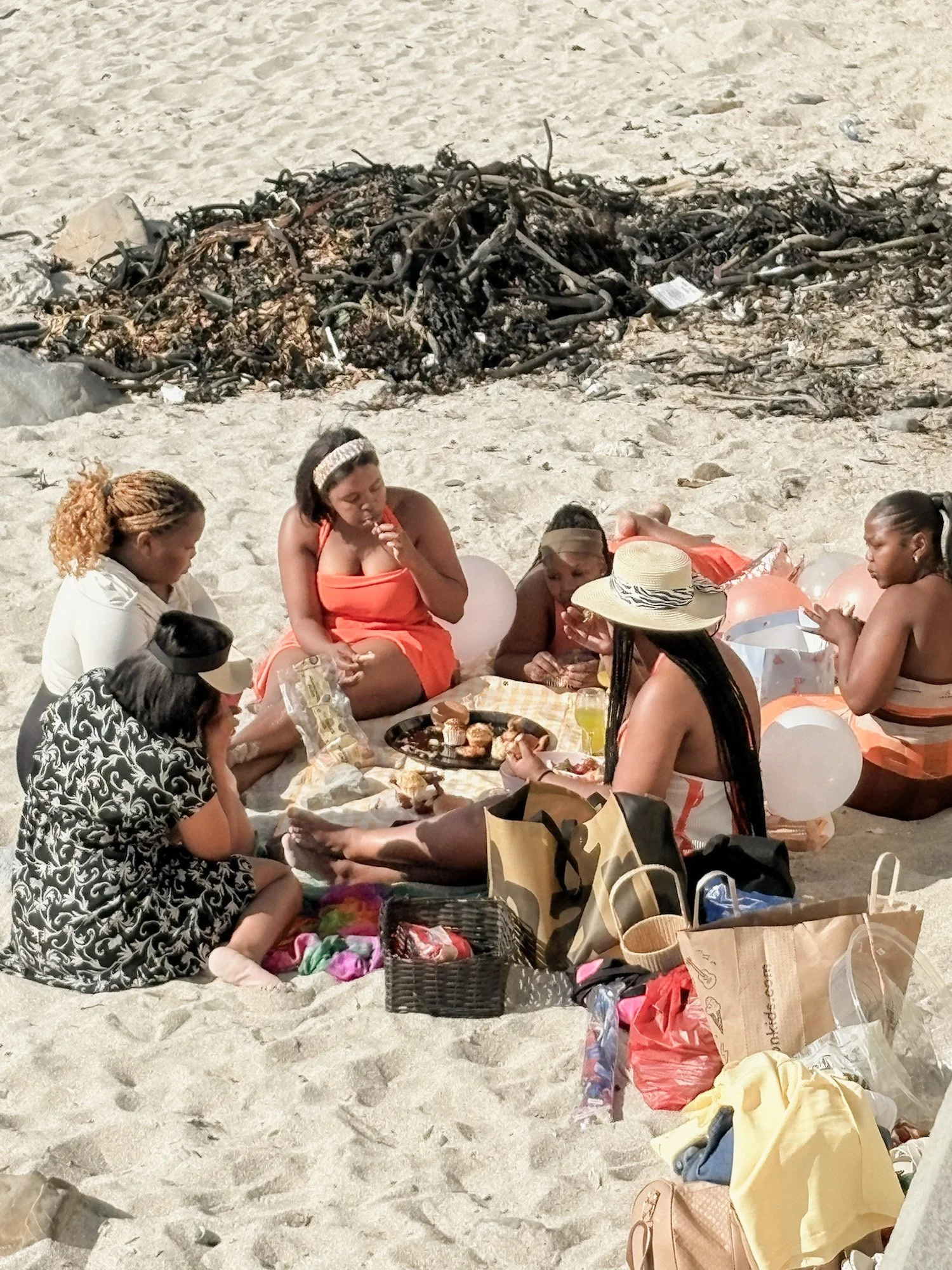 Groep vrouwen tijdens een picknick op het strand in Zuid-Afrika.