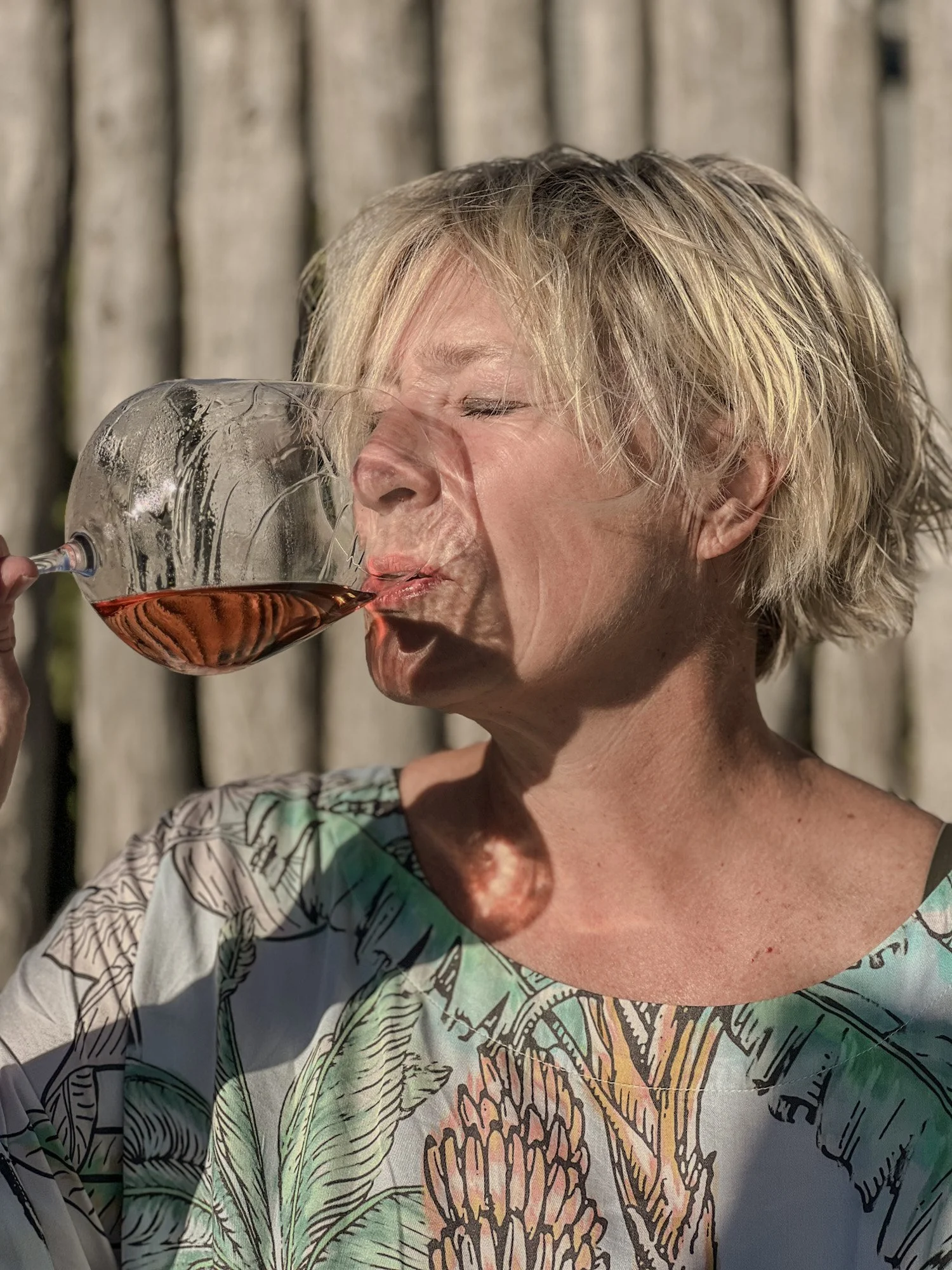 Vrouw drinkt rosé wijn in warm zonlicht aan de Zuid-Afrikaanse kust.