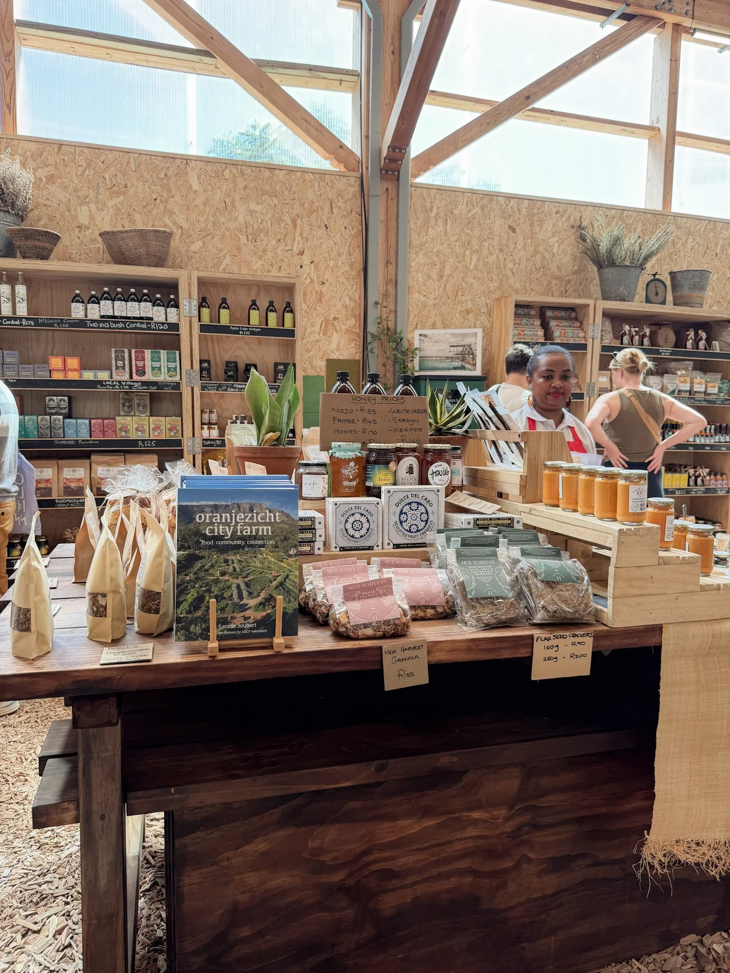 Tafel met lokale producten zoals granola, honing en kruiden in Oranjezicht City Farm.