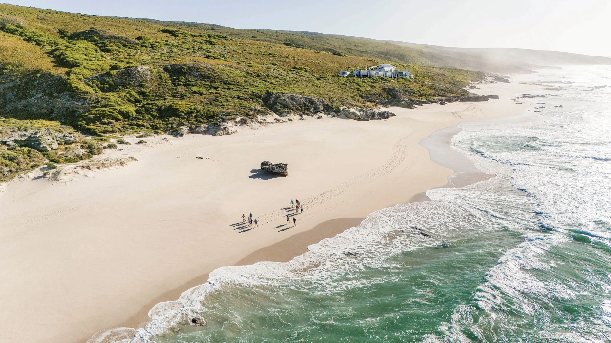 Wandelaars op een verlaten strand langs de kust van Zuid-Afrika.