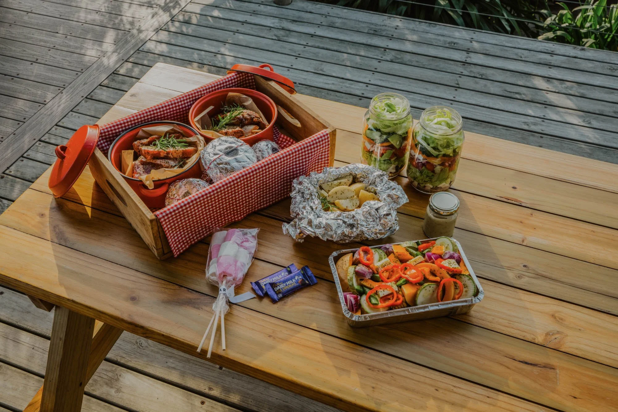 Braaimaaltijd met vlees, salades en groenten op het terras van AfriCamps at Oakhurst bij Wilderness.