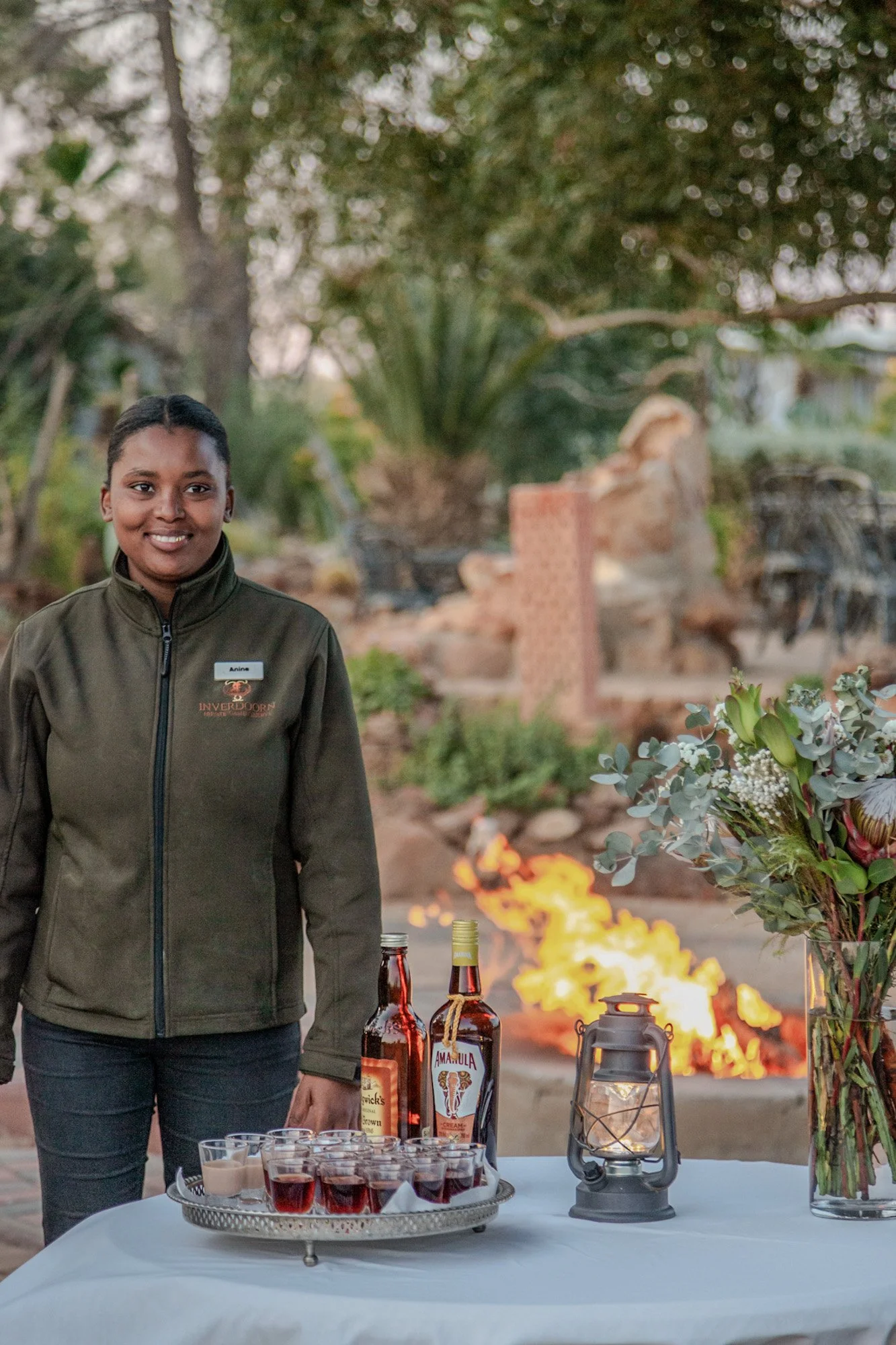 Gastvrouw staat trots en lachend naast dienblad met Amarula likeur in Zuid-Afrika.