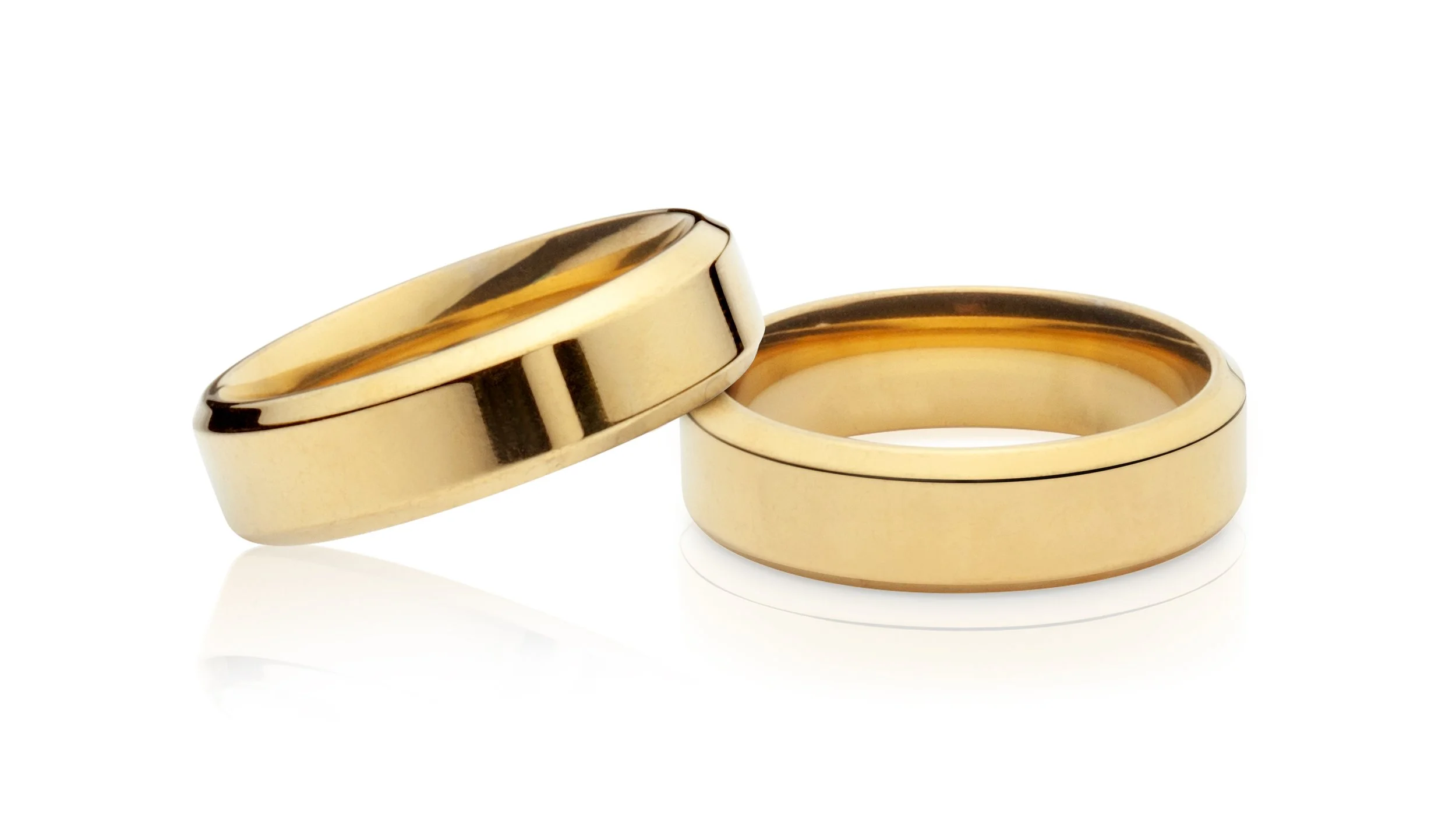 Professional jewelry picture of two gold wedding bands, one slightly tilted, on a white background.