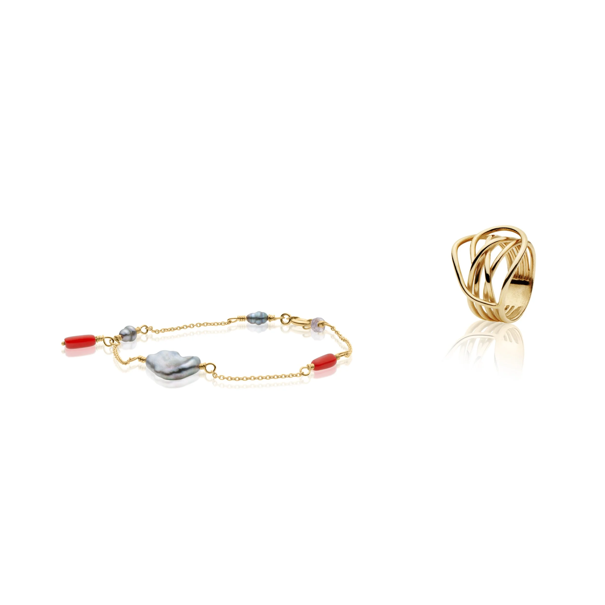 Professional jewelry picture of gold ring with intertwined design and a necklace with pearls, red beads, and gold chain.