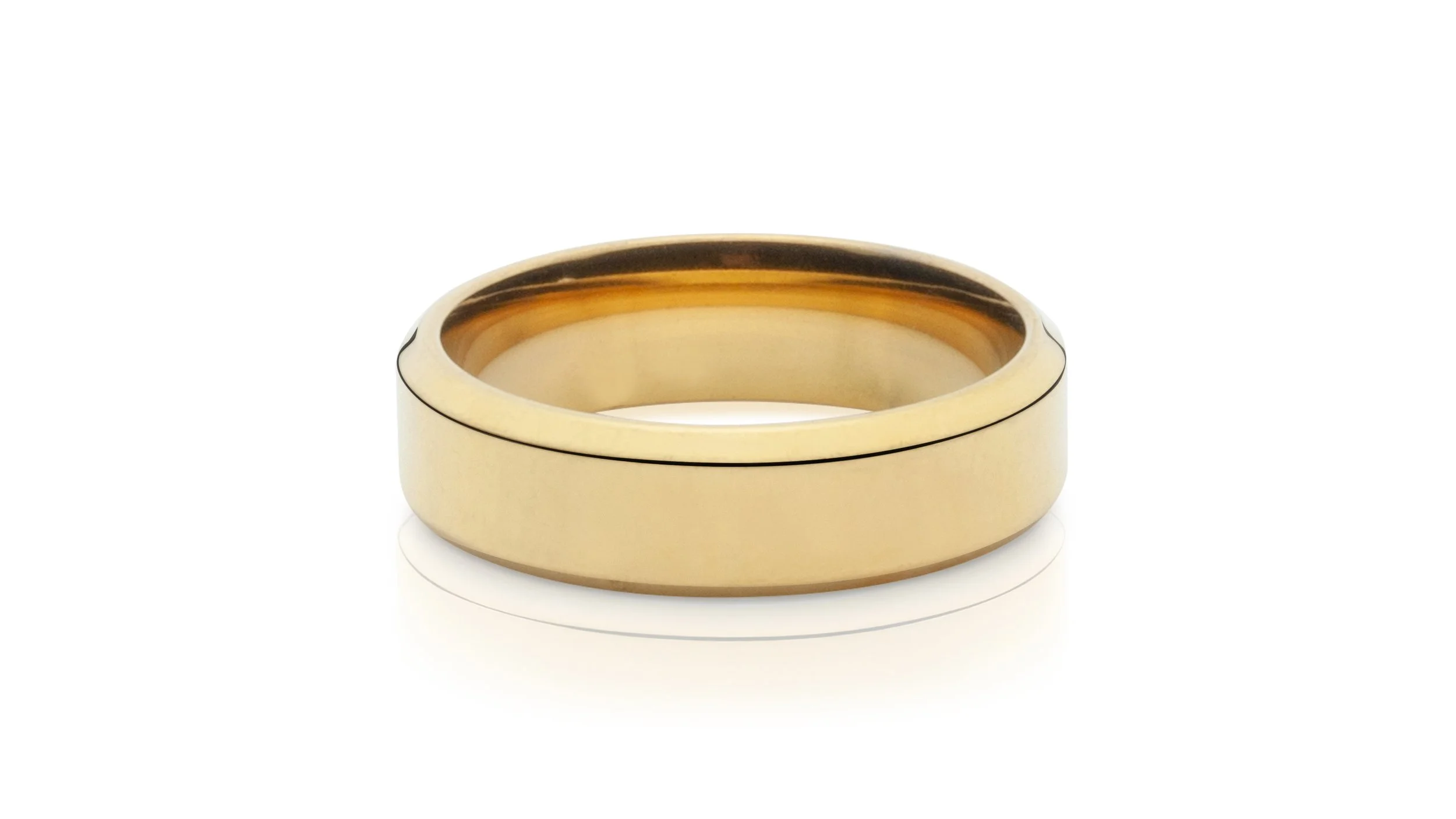 Professional jewelry picture of close-up view of a gold wedding band with a black line detail on a white surface.