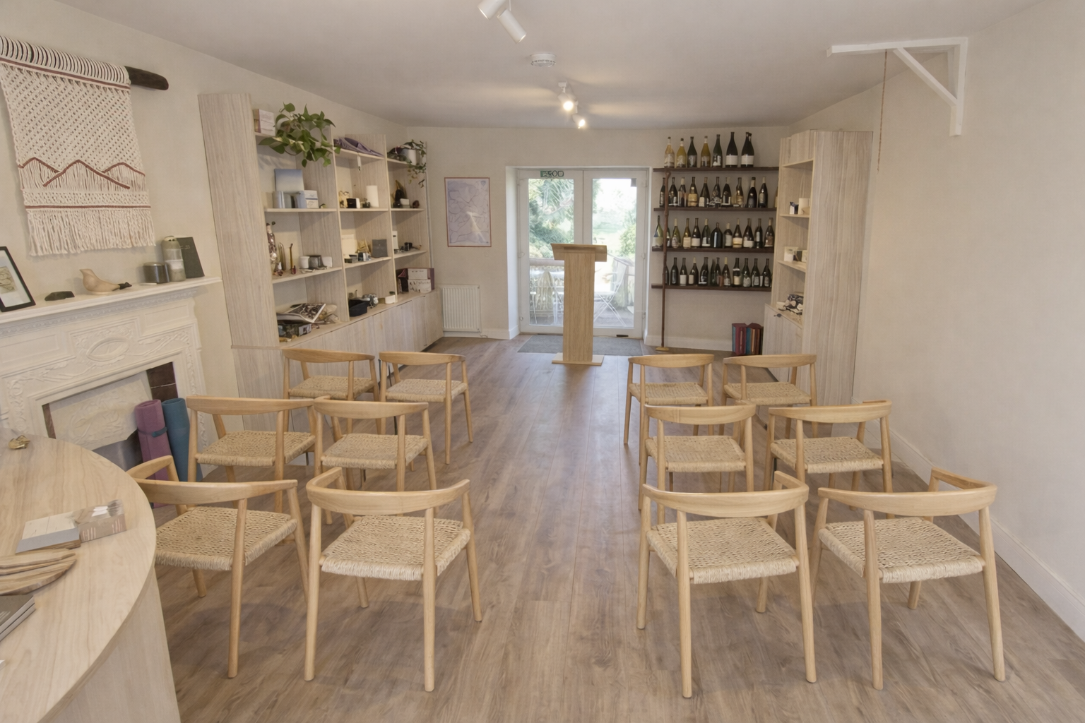 Our shop floor can be set up for a presentation or meeting with wooden chairs arranged in rows facing a wooden podium in front of glass doors leading outside.