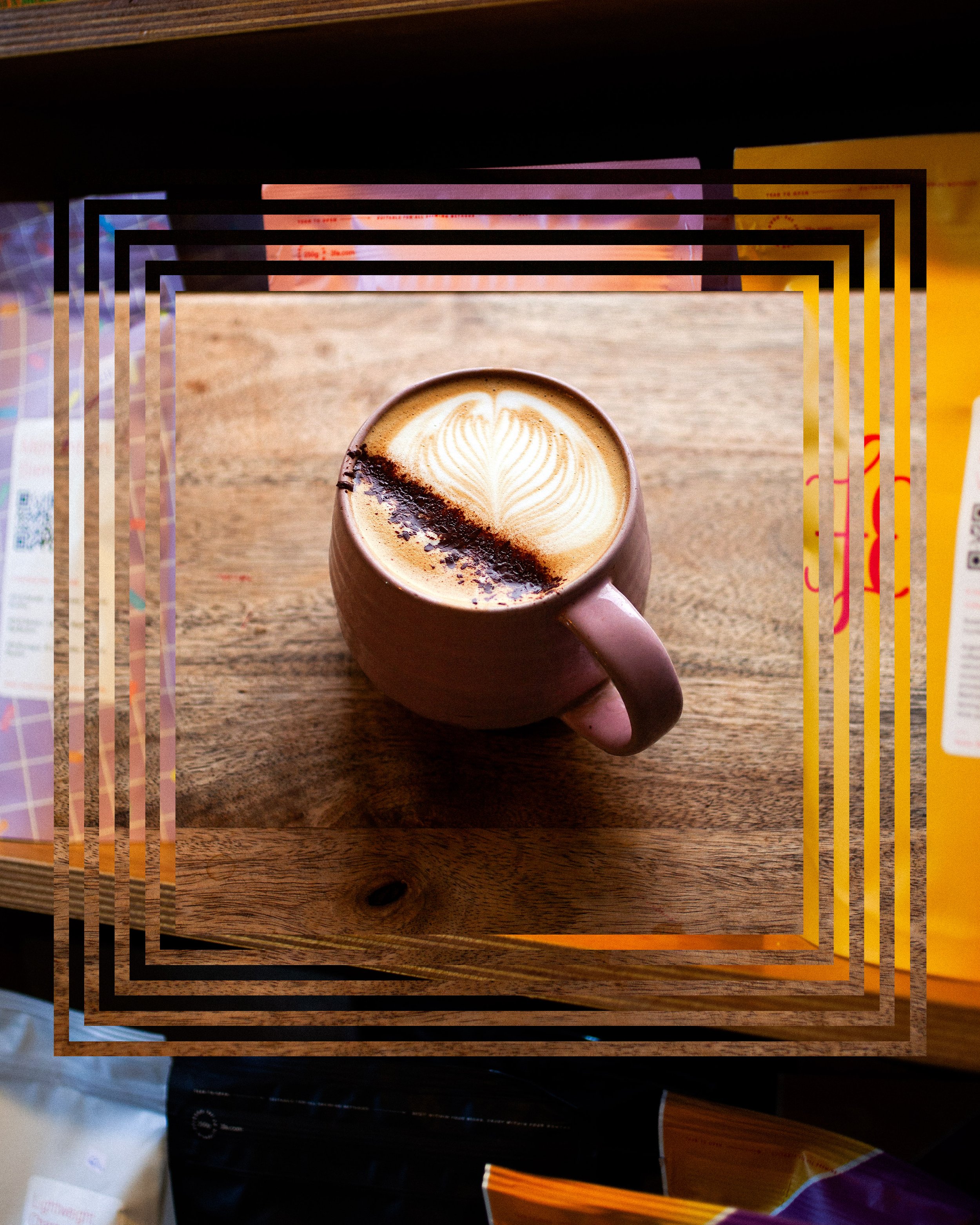 A pink mug filled with latte art featuring a leaf design, sitting on a wooden surface.