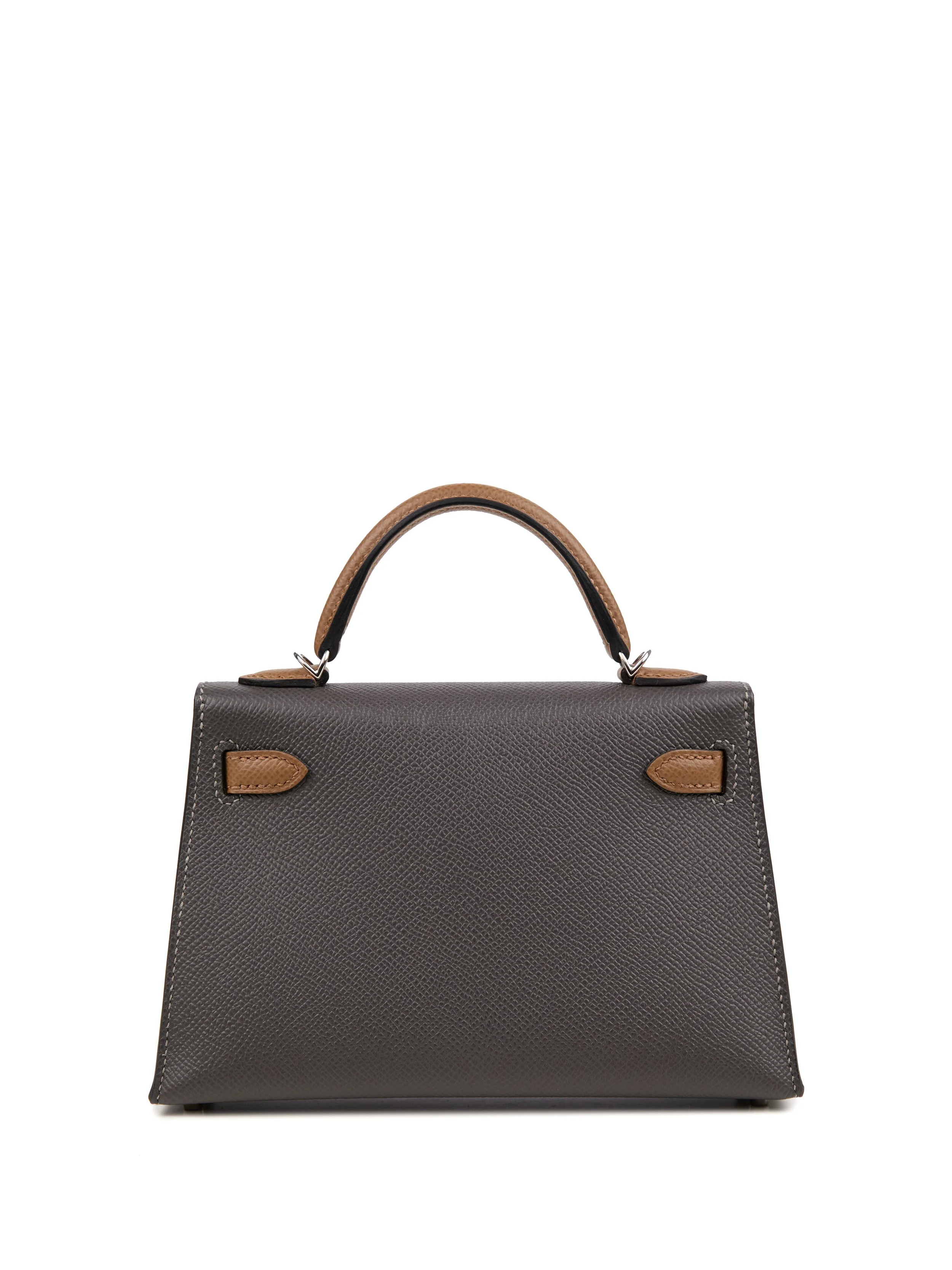 A black structured handbag with brown leather accents and handle, isolated on a white background.