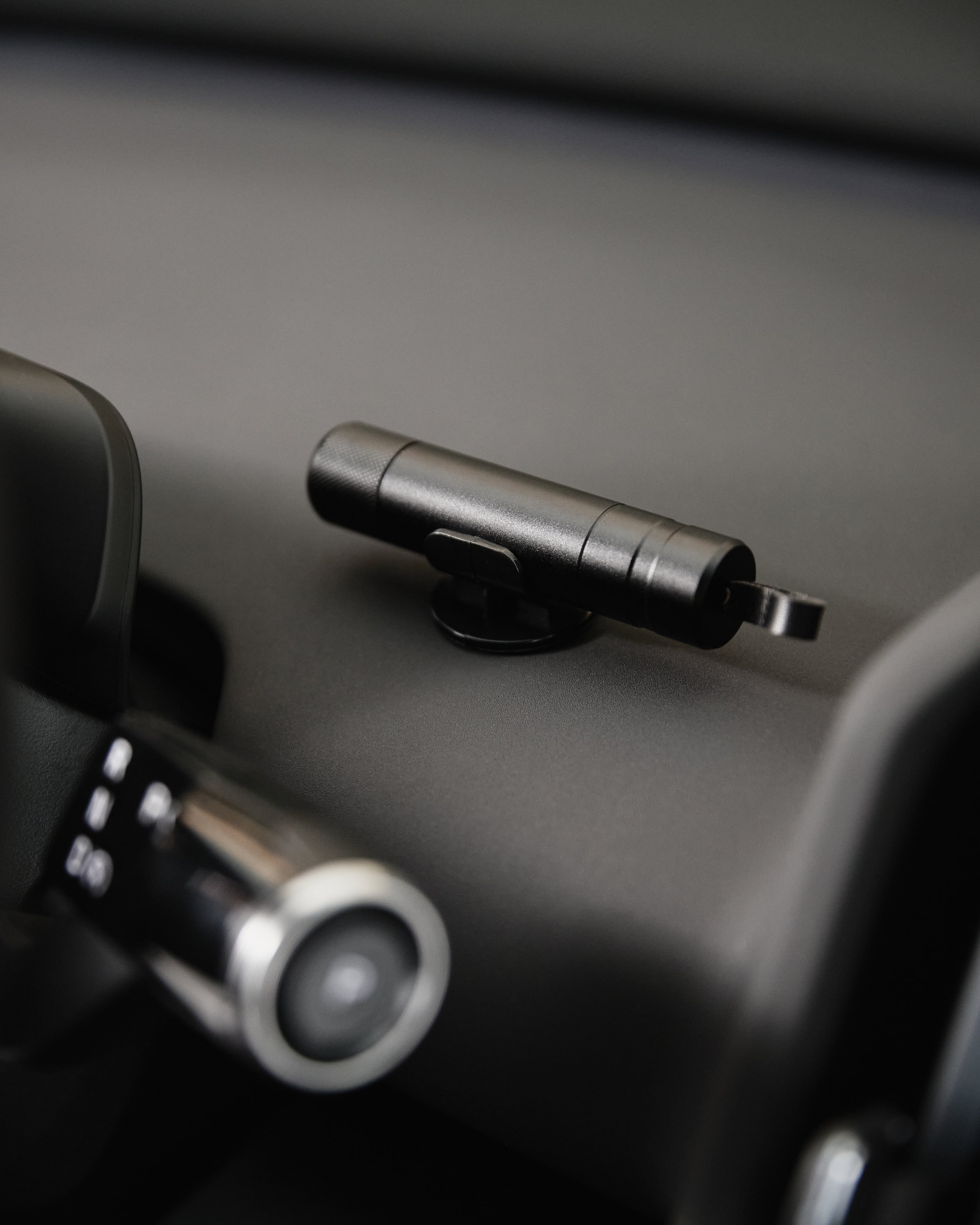 Dispositivo eletrônico preto fixado na superfície de um painel, possivelmente na cabine de um veículo.
A black electronic device attached to the surface of a dashboard, possibly in the cabin of a vehicle.