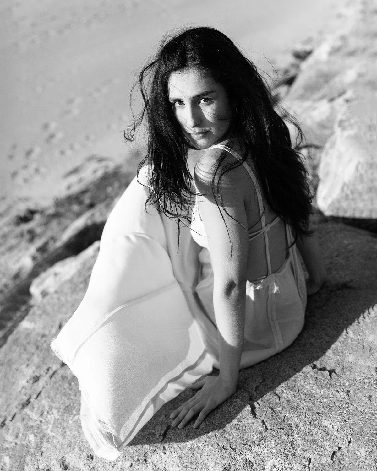 Mulher com cabelo escuro e comprido sentado numa rocha, olhando para a câmera, ao ar livre, em um ambiente externo.
Woman with long dark hair sitting on a rock, looking at the camera, outdoors, in an outdoor setting.