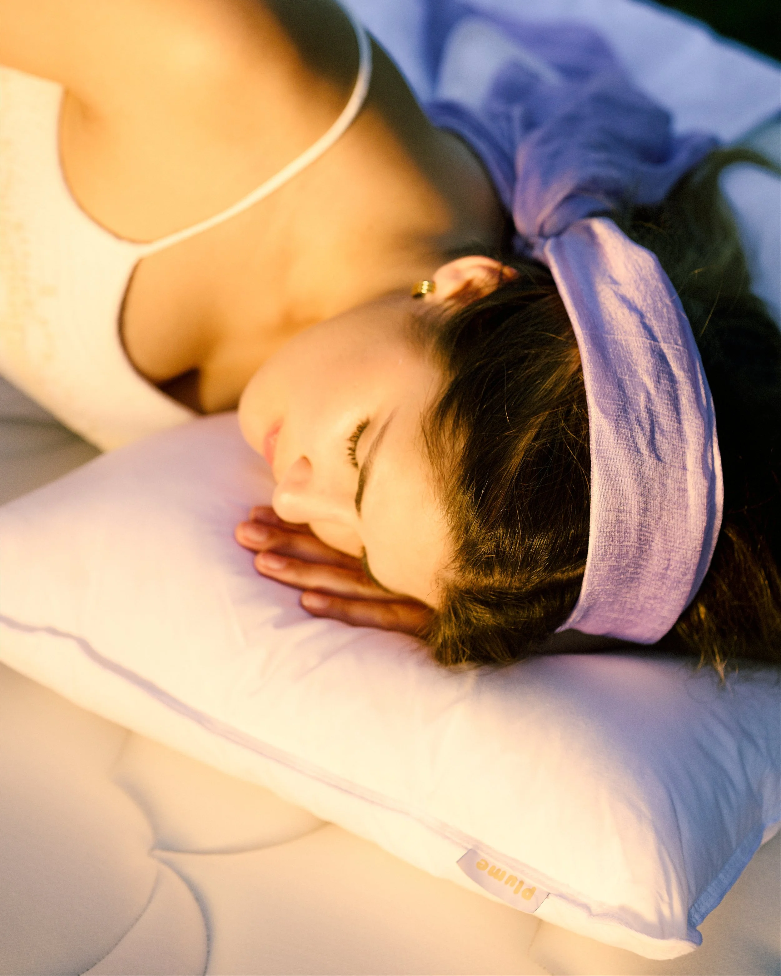 A woman sleeping on a pillow with her head turned sideways, wearing a headband and earrings.