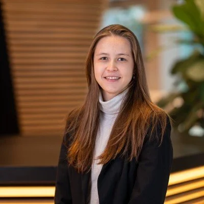 Portrait of a young woman with long hair in a black blazer indoors.