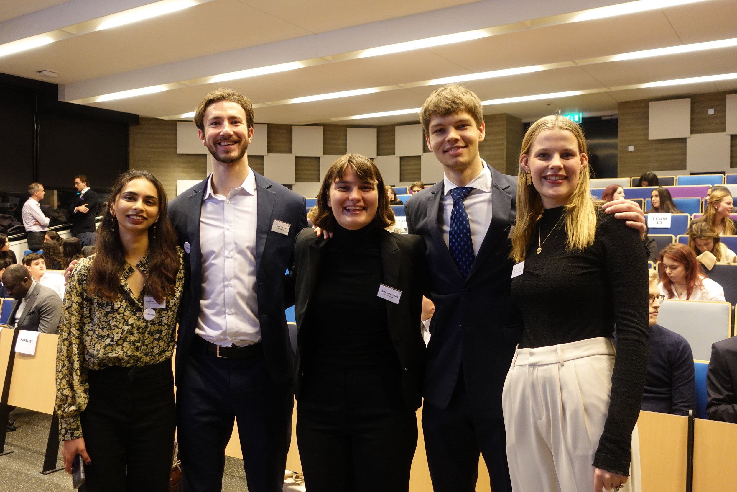 Five students posing in a lecture hall during the I DO Impact Event 2022 at Erasmus University.