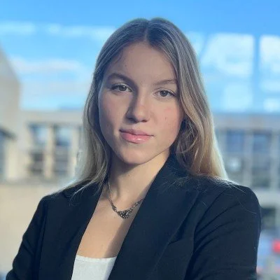 Portrait of a young woman in a black blazer outdoors.