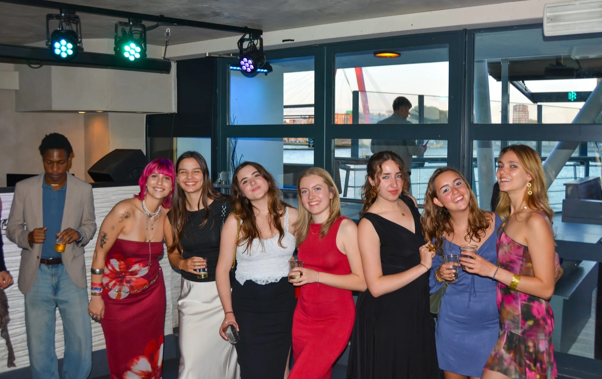A group of young adults dressed for an evening event, posing together indoors.