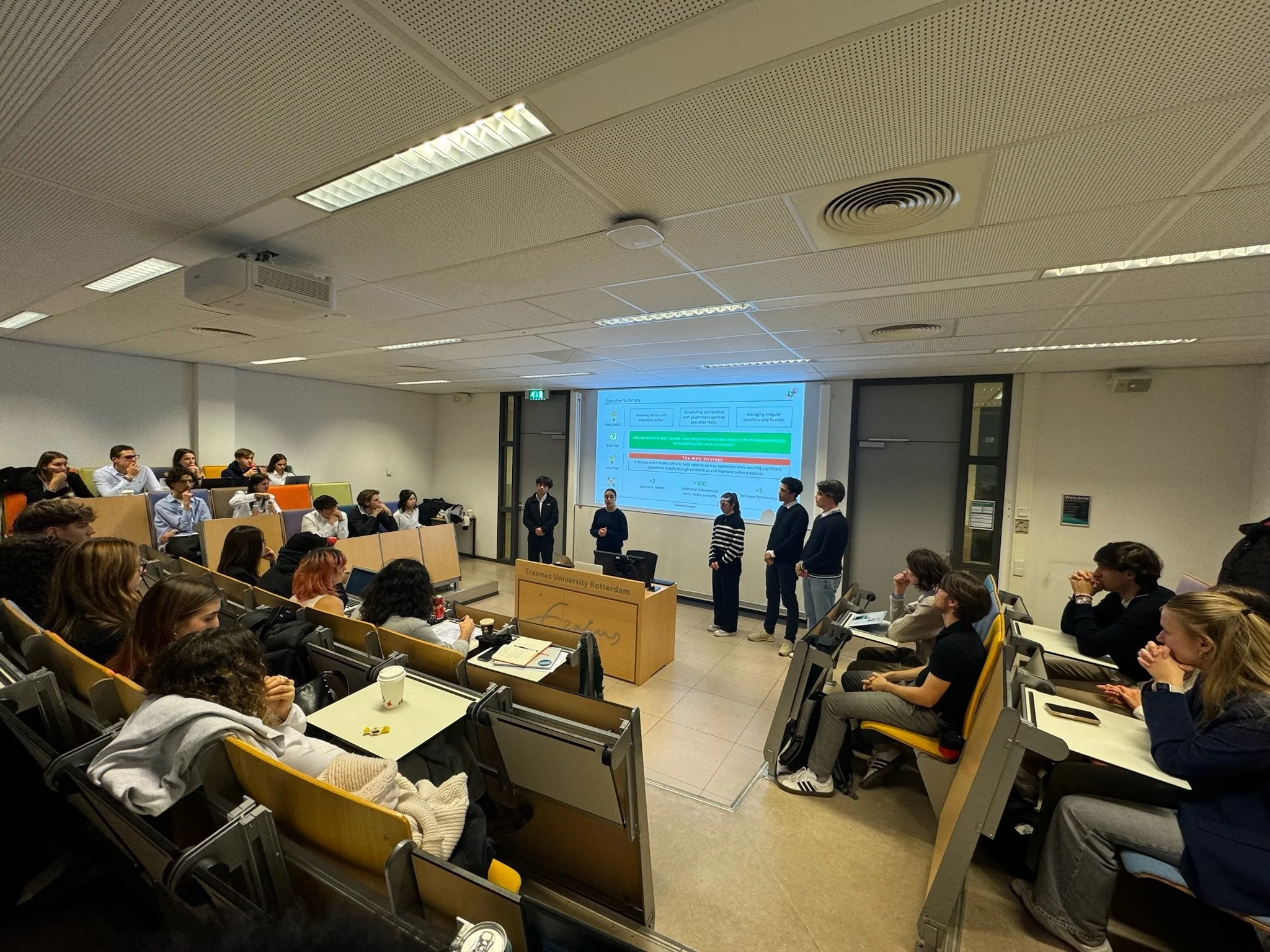 Students presenting in a lecture hall at Erasmus University, audience seated and watching.