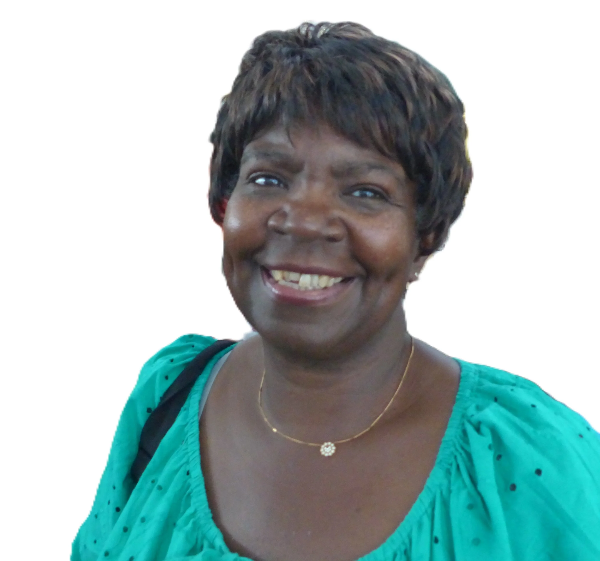 Home-Start trustee, A smiling woman with short, dark hair wearing a teal top, gold necklace, and carrying a black bag.