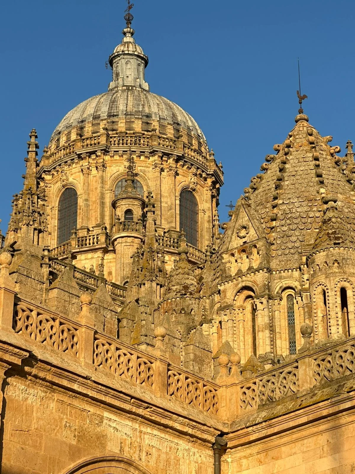 Close-up of a historic European cathedral's ornate stone architecture with a large domed roof against a clear blue sky.