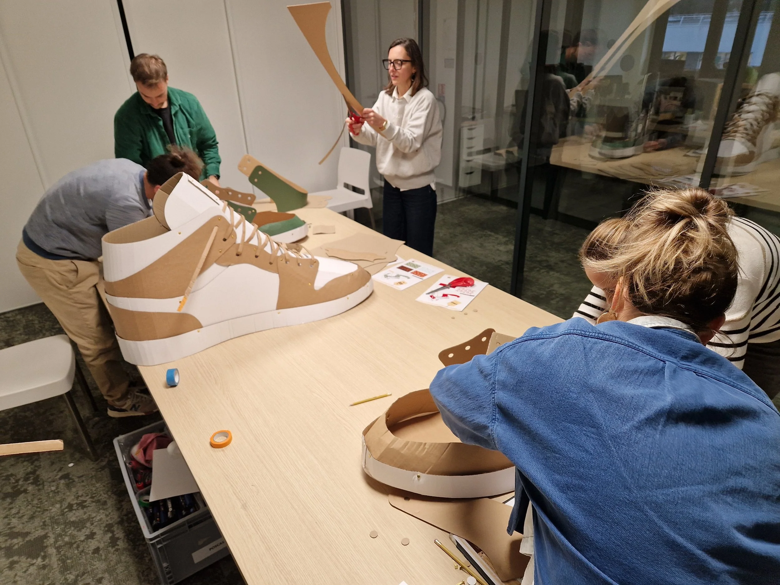 Moment de travail ensemble sur un projet collaboratif de construction de chaussure en carton géante lors d'une réunion