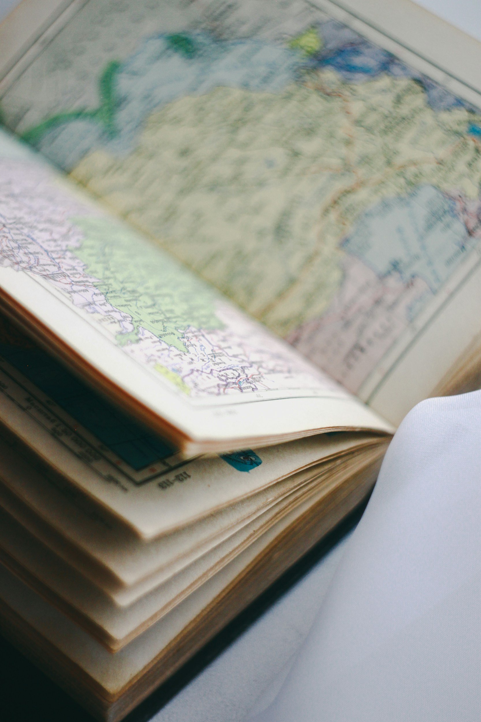 Open travel or road atlas showing maps of regions, with pages turned and visible folds.