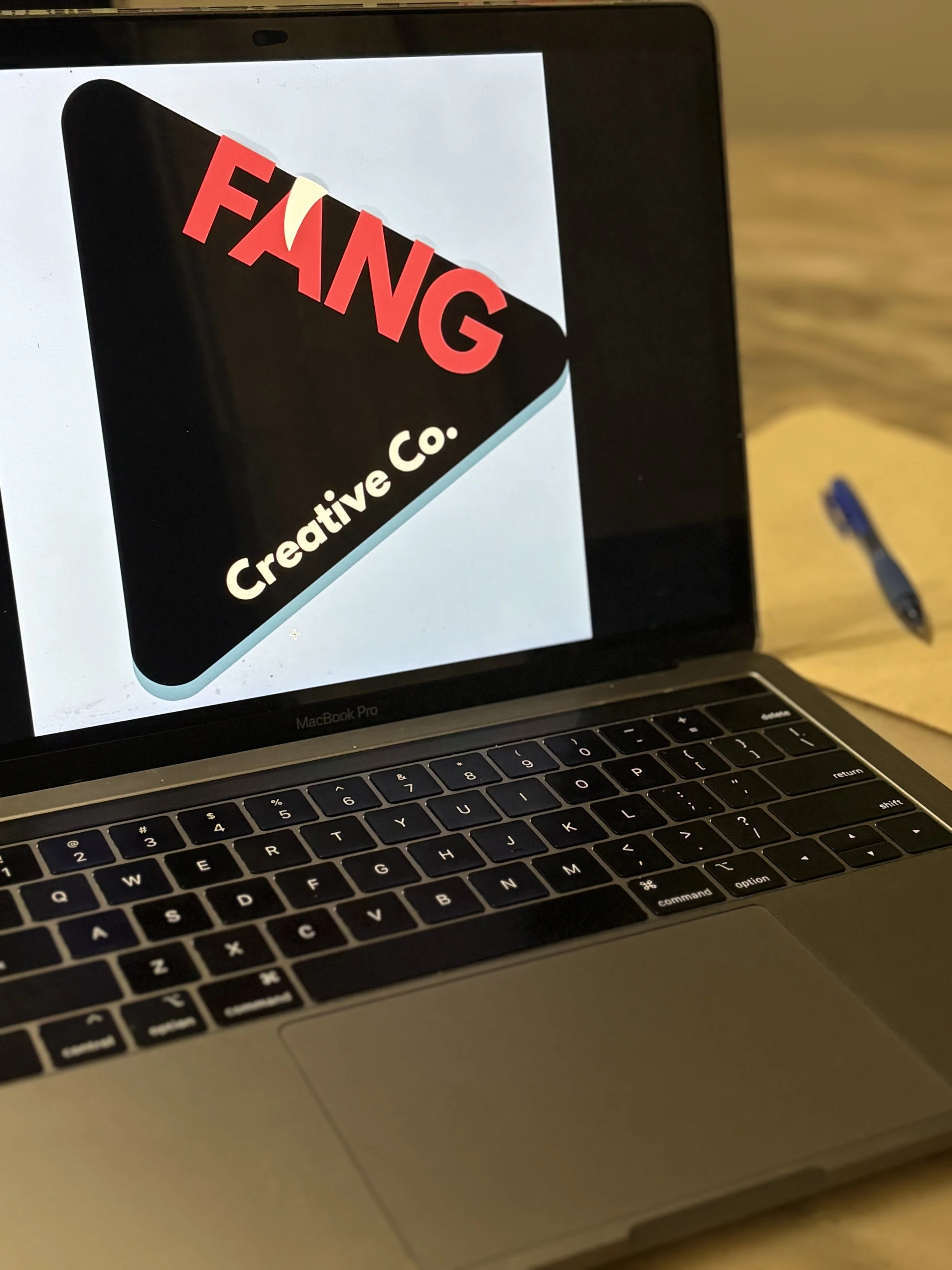Close-up of a laptop screen displaying a logo for 'FANG Creative Co.' with a black and white background and red text.